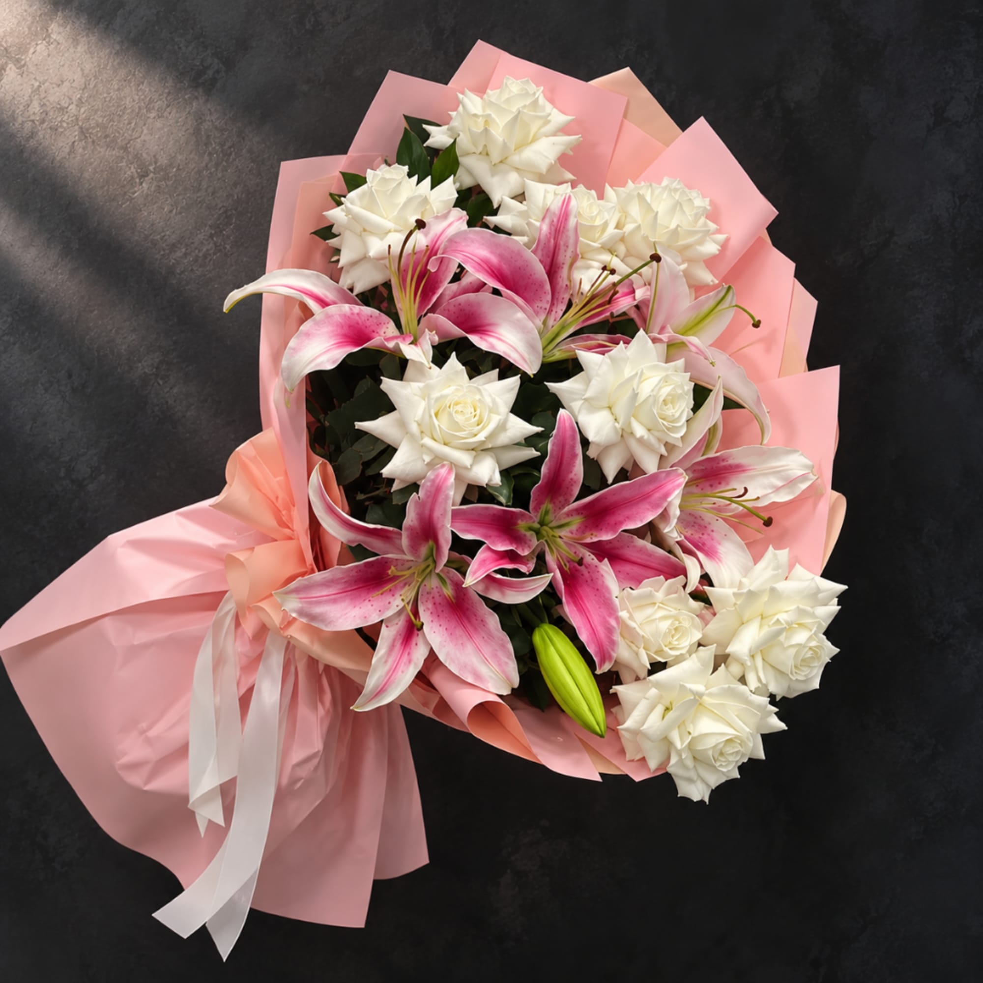 Pink and white bouquet with lilies and roses wrapped in pink paper