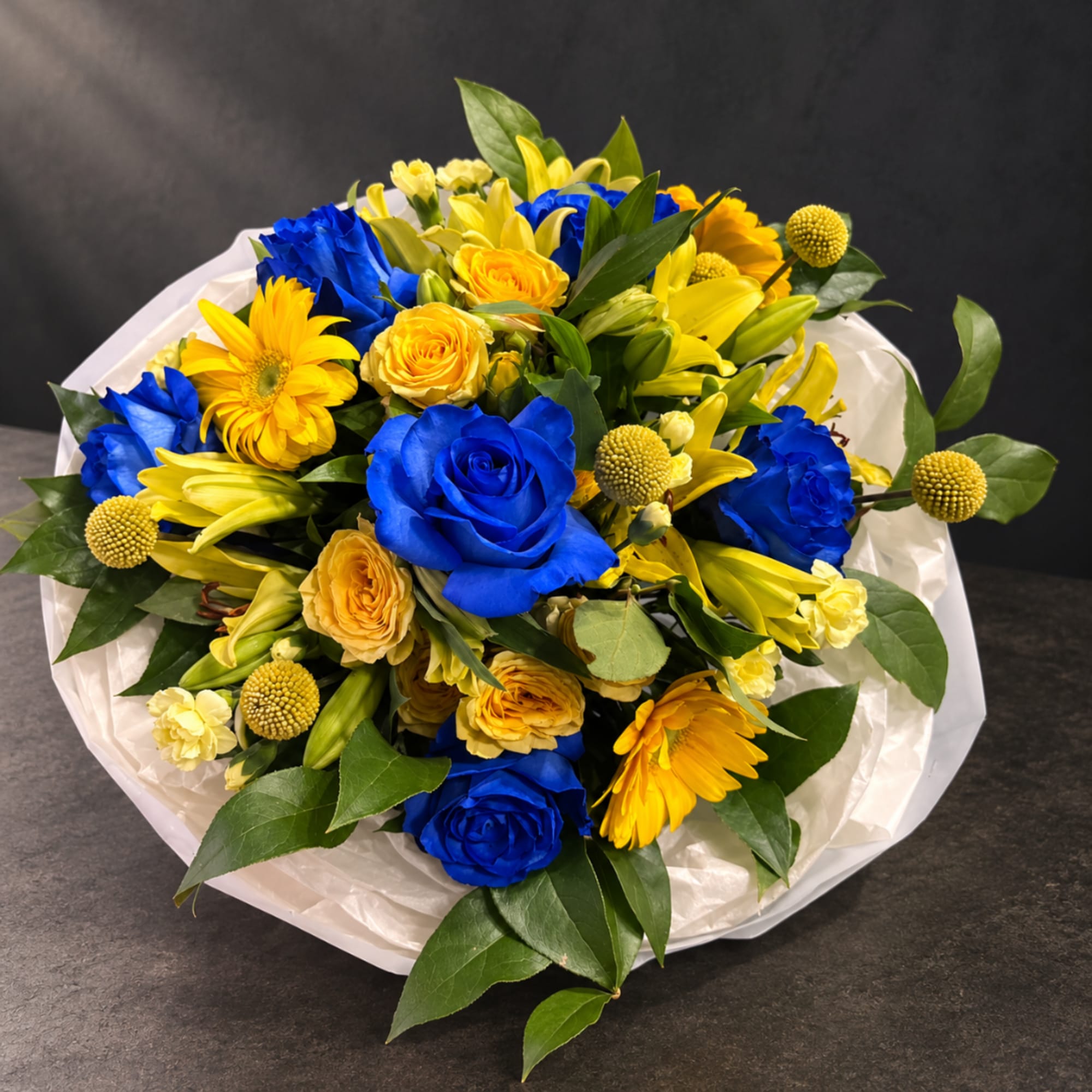 Bouquet of blue roses and yellow flowers wrapped in white paper