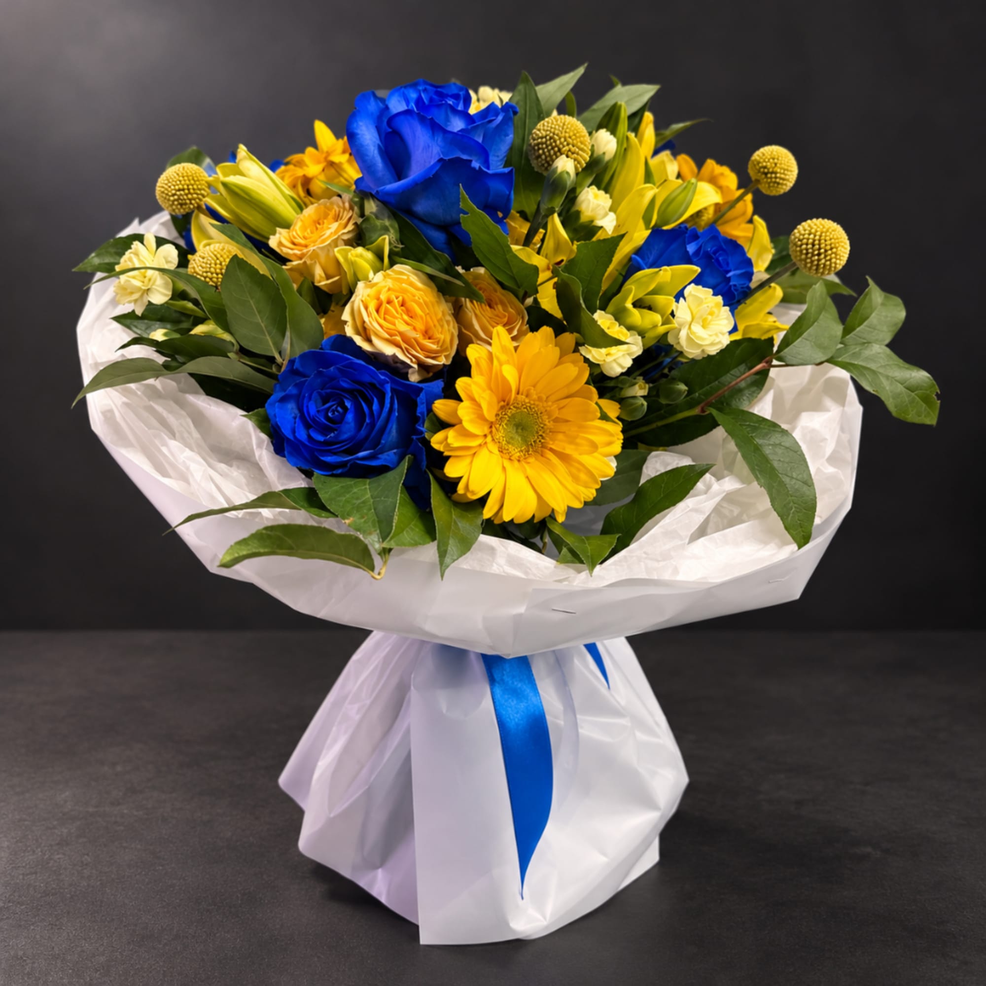 Bouquet of blue and yellow flowers wrapped in white paper with a blue ribbon