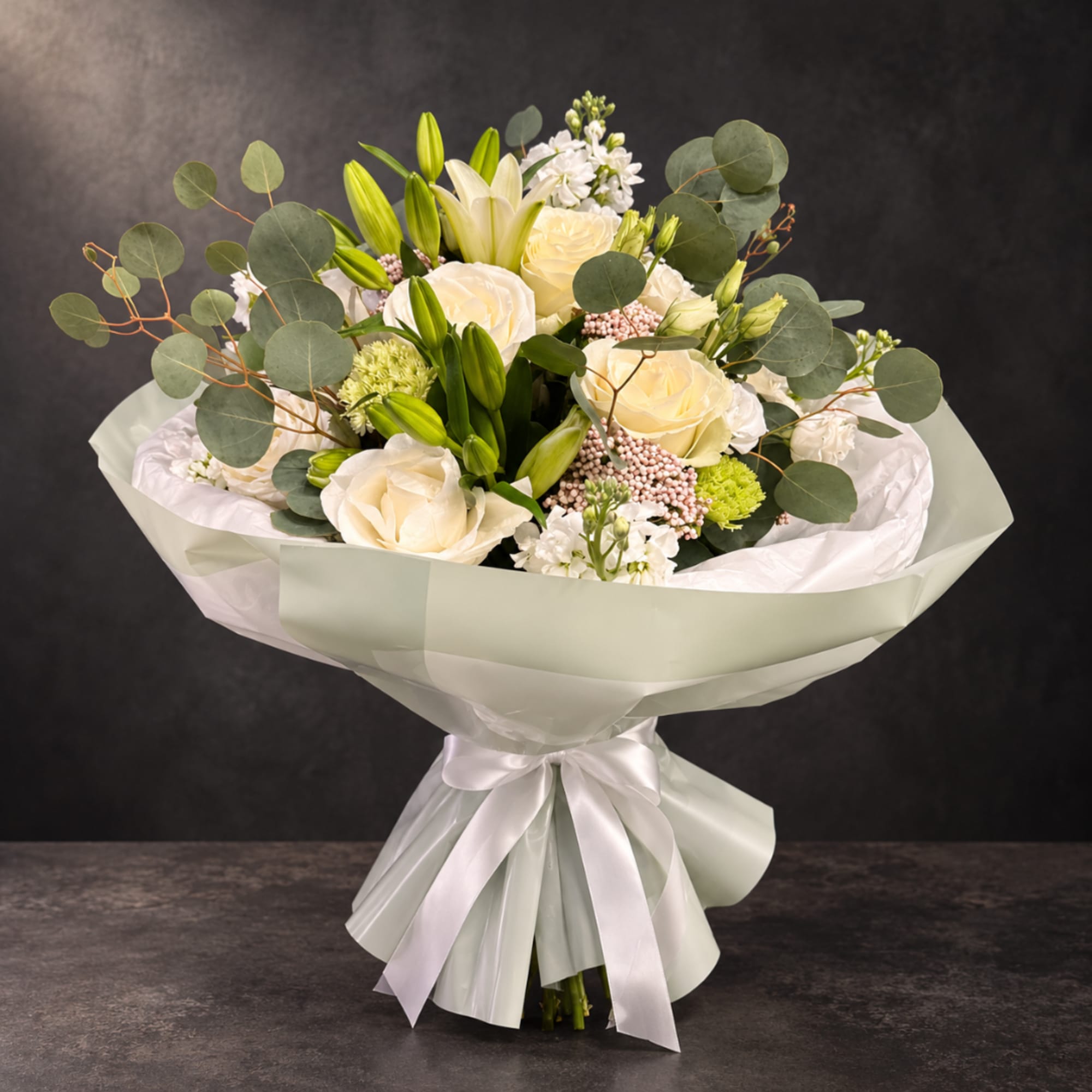 Bouquet of cream roses and white lilies wrapped in pale paper