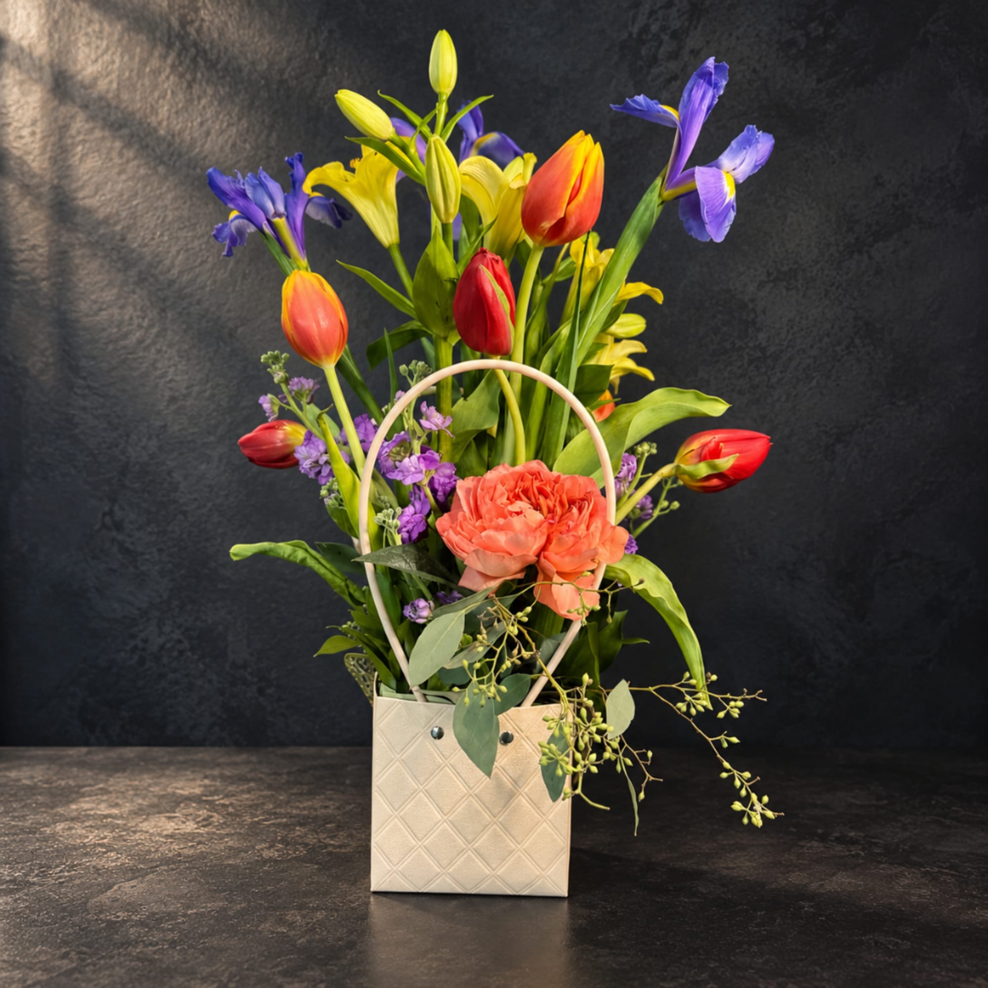 Colorful mixed bouquet in a cream handled box with tulips and iris