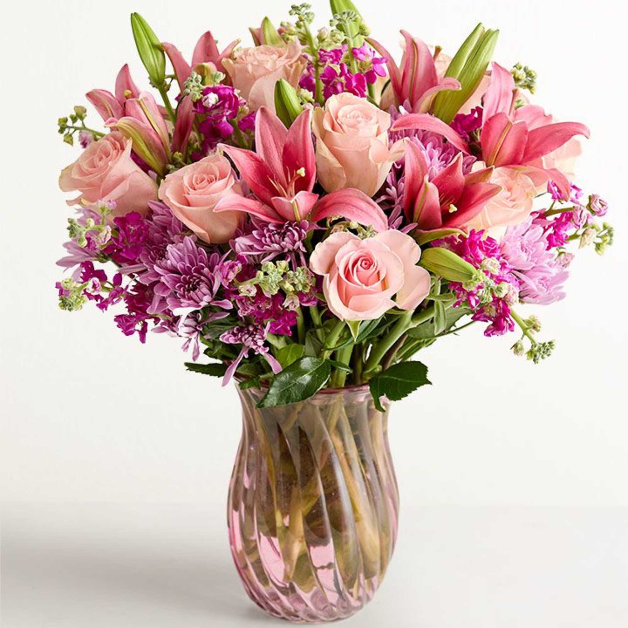 Soft blush roses and open pink lilies create a romantic, feminine focal