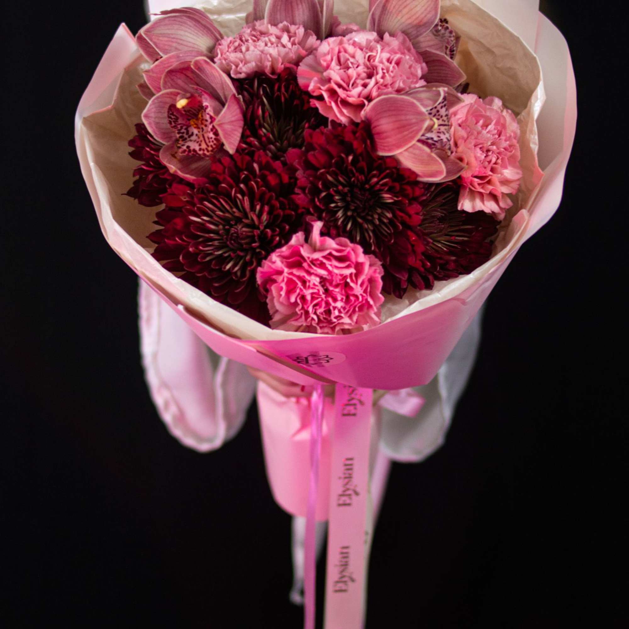 Deep burgundy blooms, soft blush carnations, and elegant orchids come together in