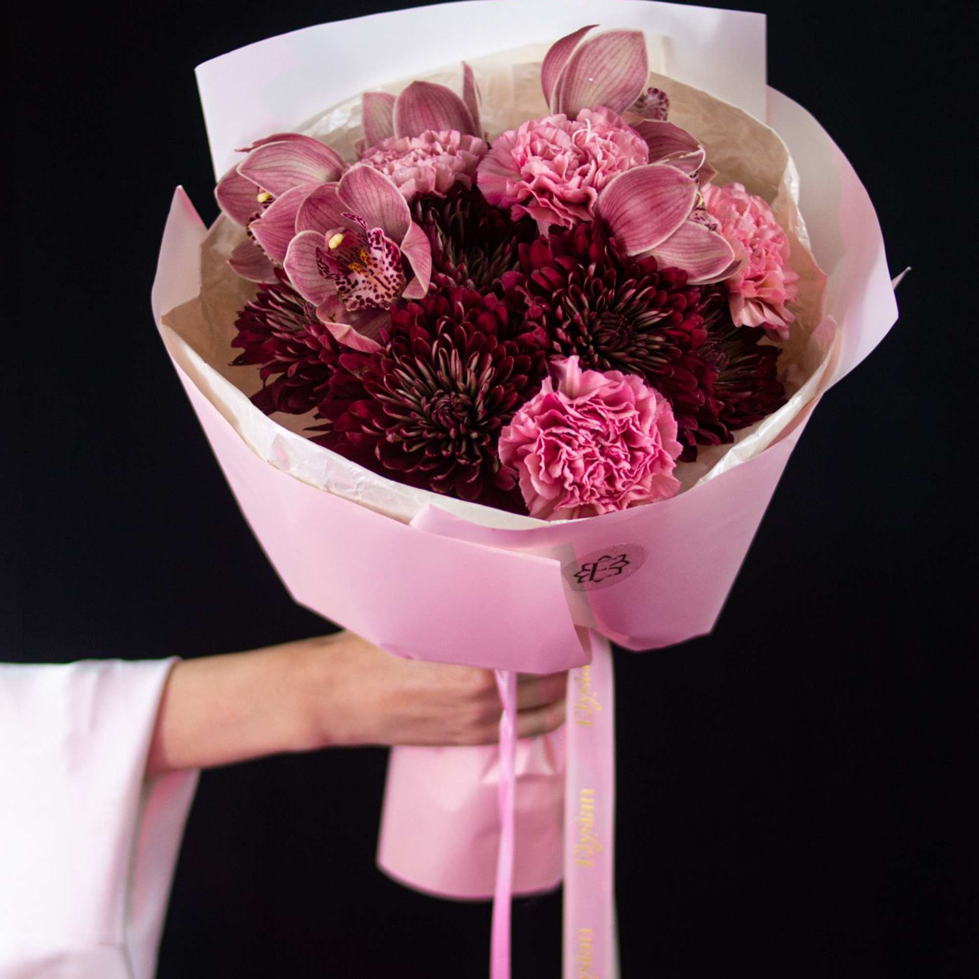 Deep burgundy blooms, soft blush carnations, and elegant orchids come together in