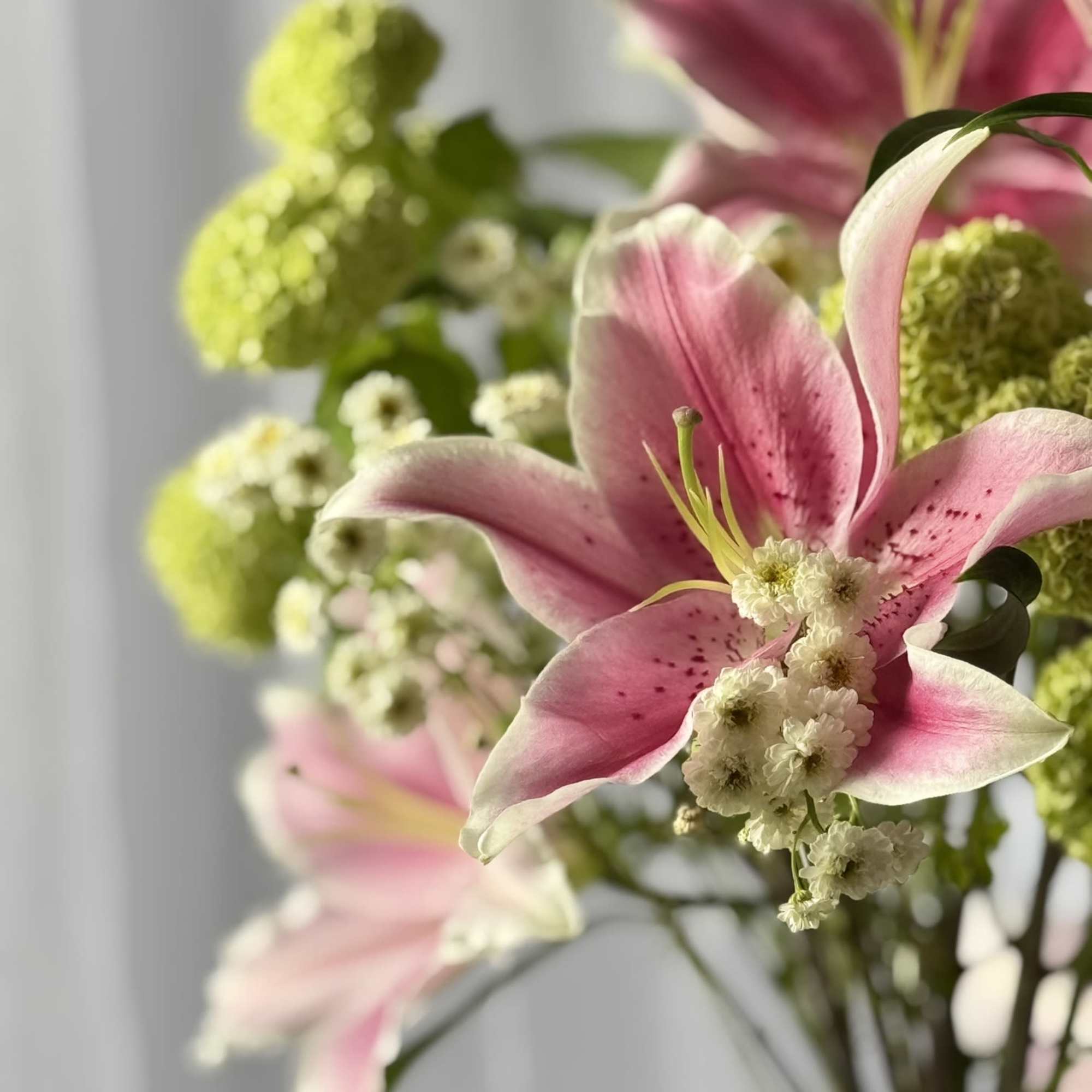 An elegant vase arrangement featuring fragrant pink oriental lilies paired with playful, photo 2 of 2