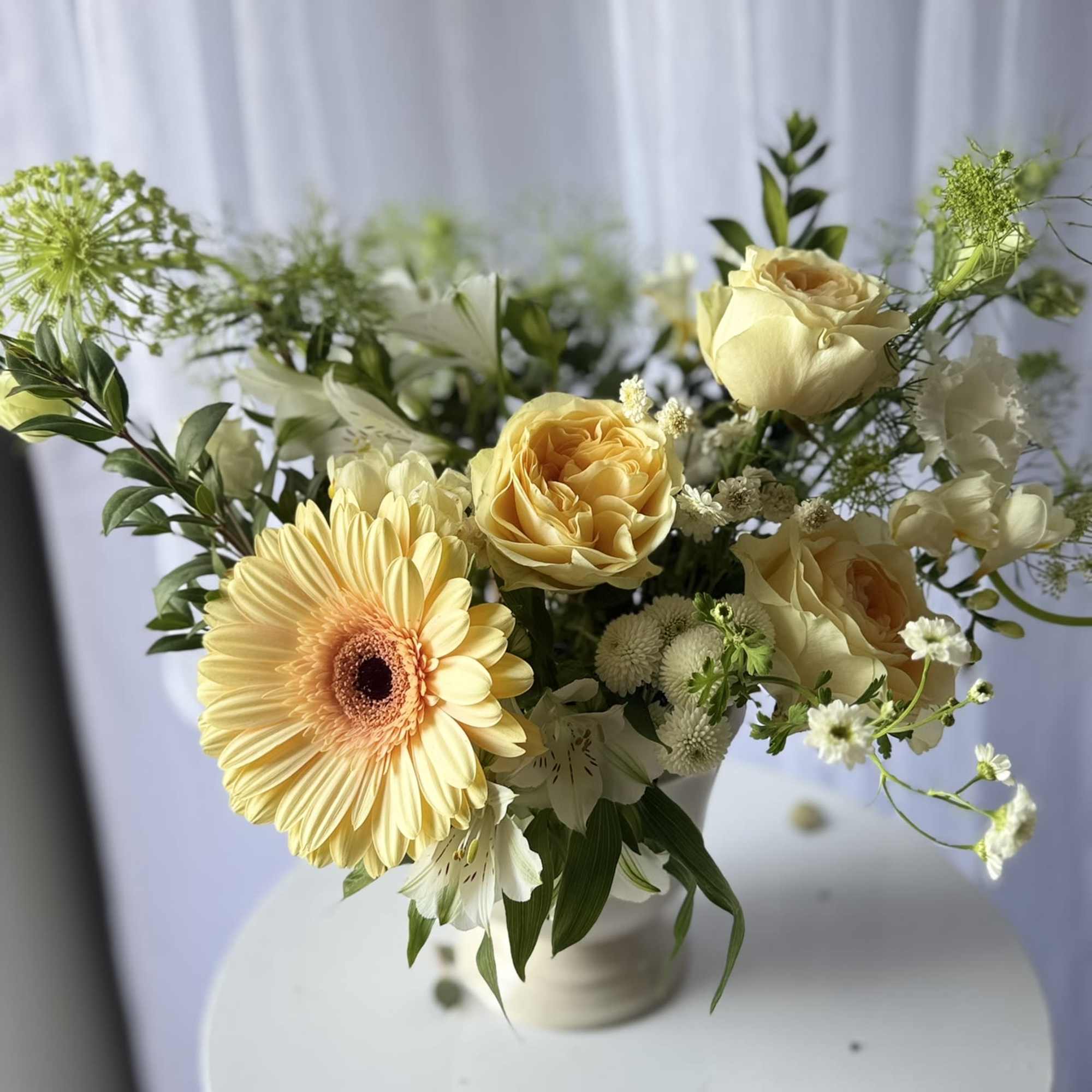 A charming garden-style arrangement featuring soft buttercream roses, a cheerful pastel gerbera, photo 2 of 2