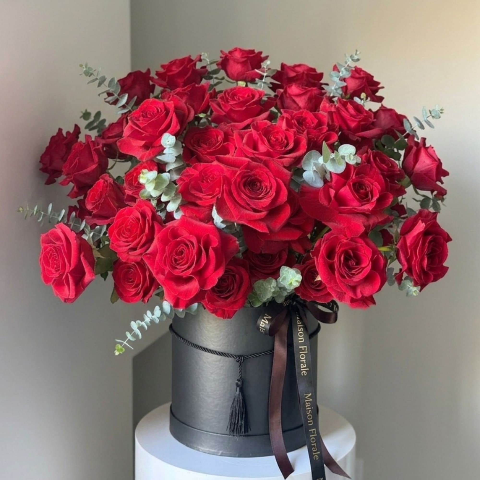 Red roses arranged in a black hat box with ribbon