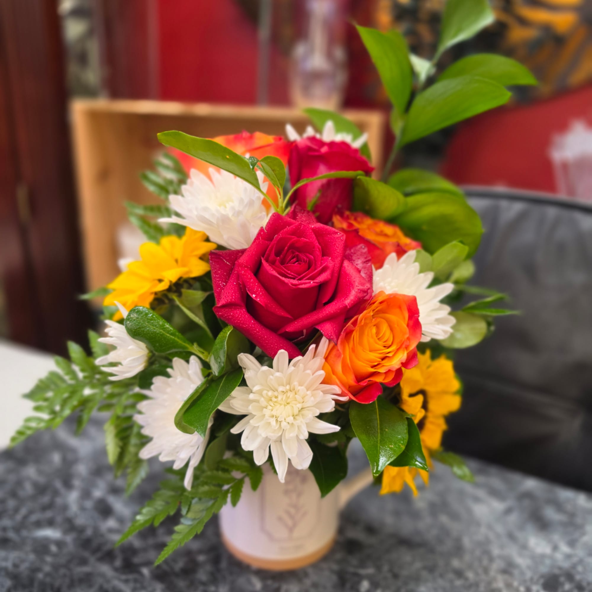 Mixed bouquet of roses and white daisies in a small vase