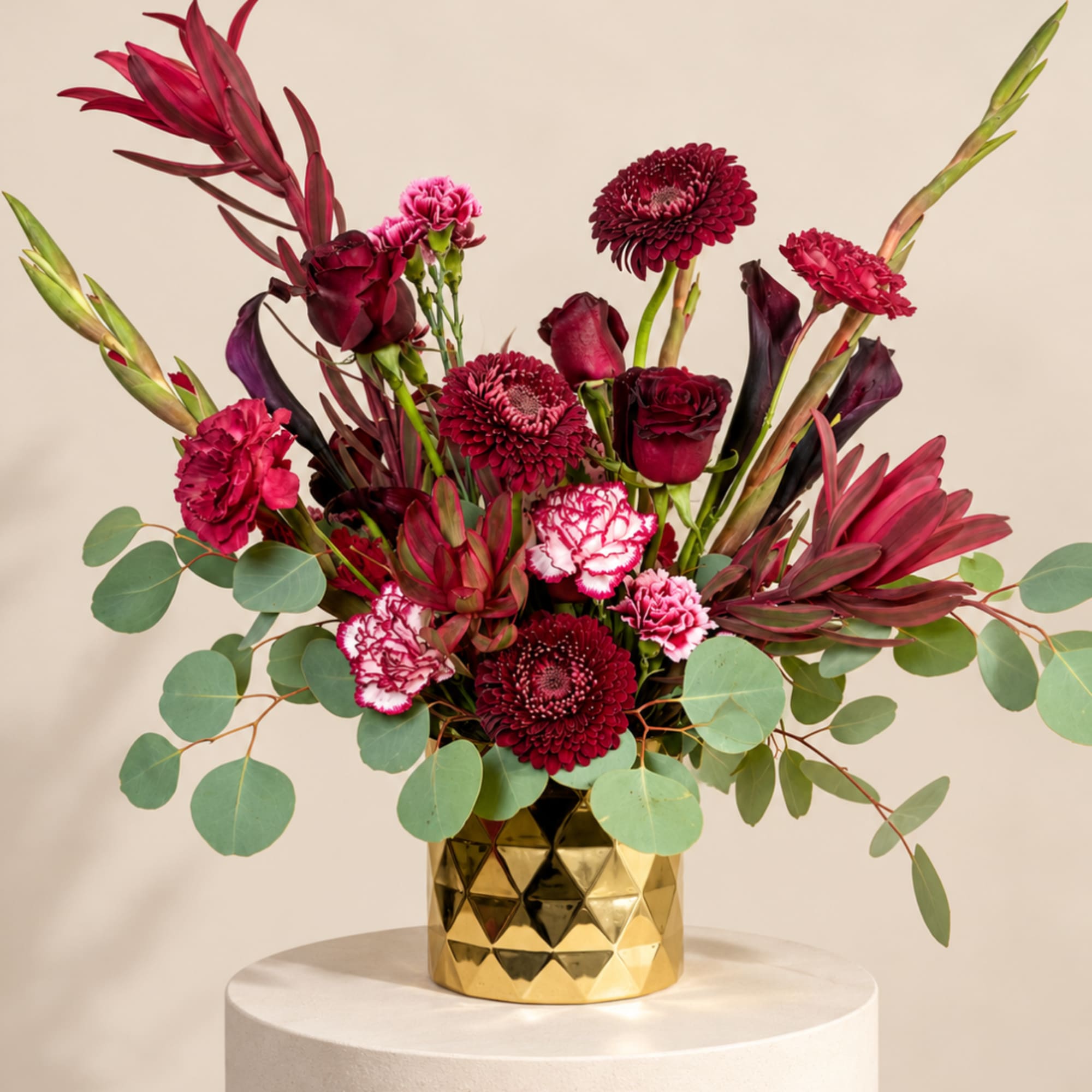 Red and pink mixed bouquet in a gold geometric vase
