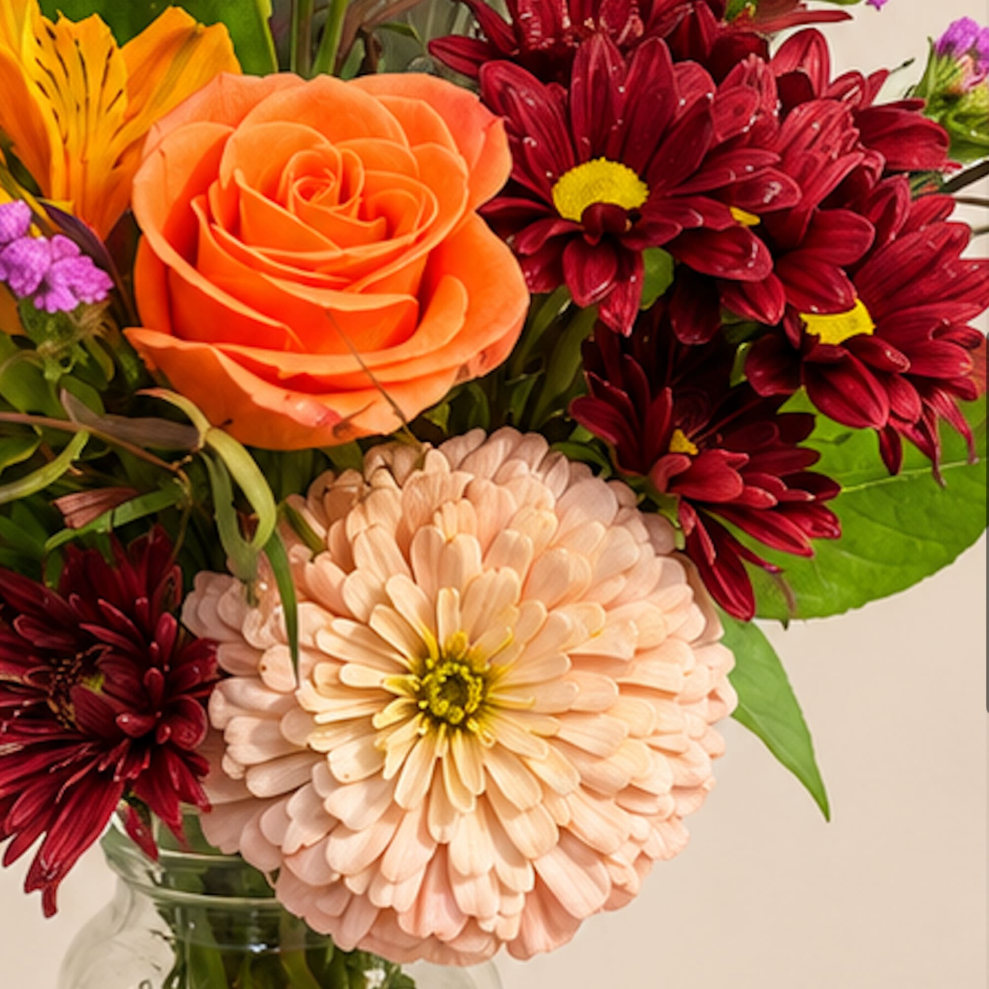 Bouquet of orange and burgundy flowers in a glass vase