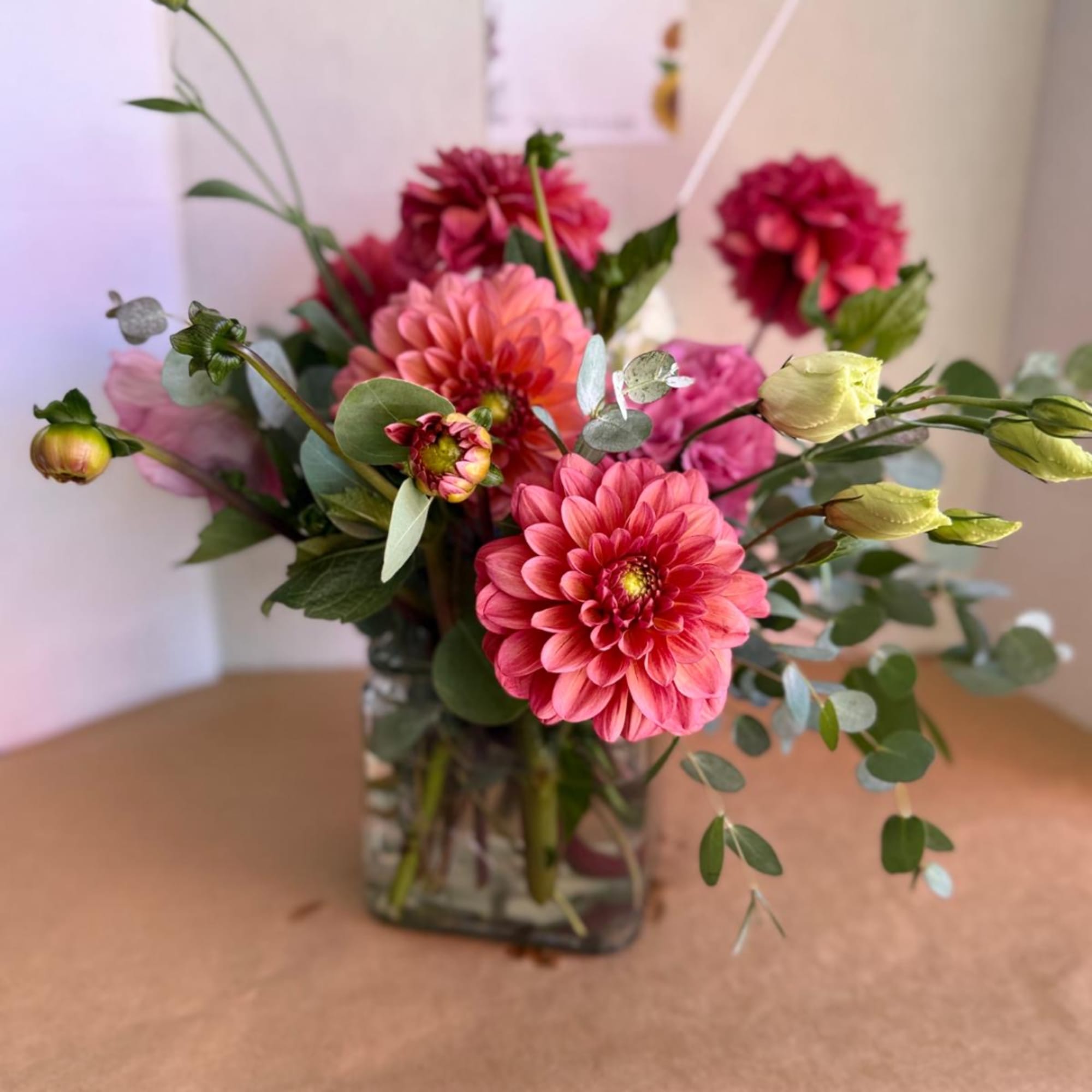 Pink and coral dahlias in a glass vase with eucalyptus