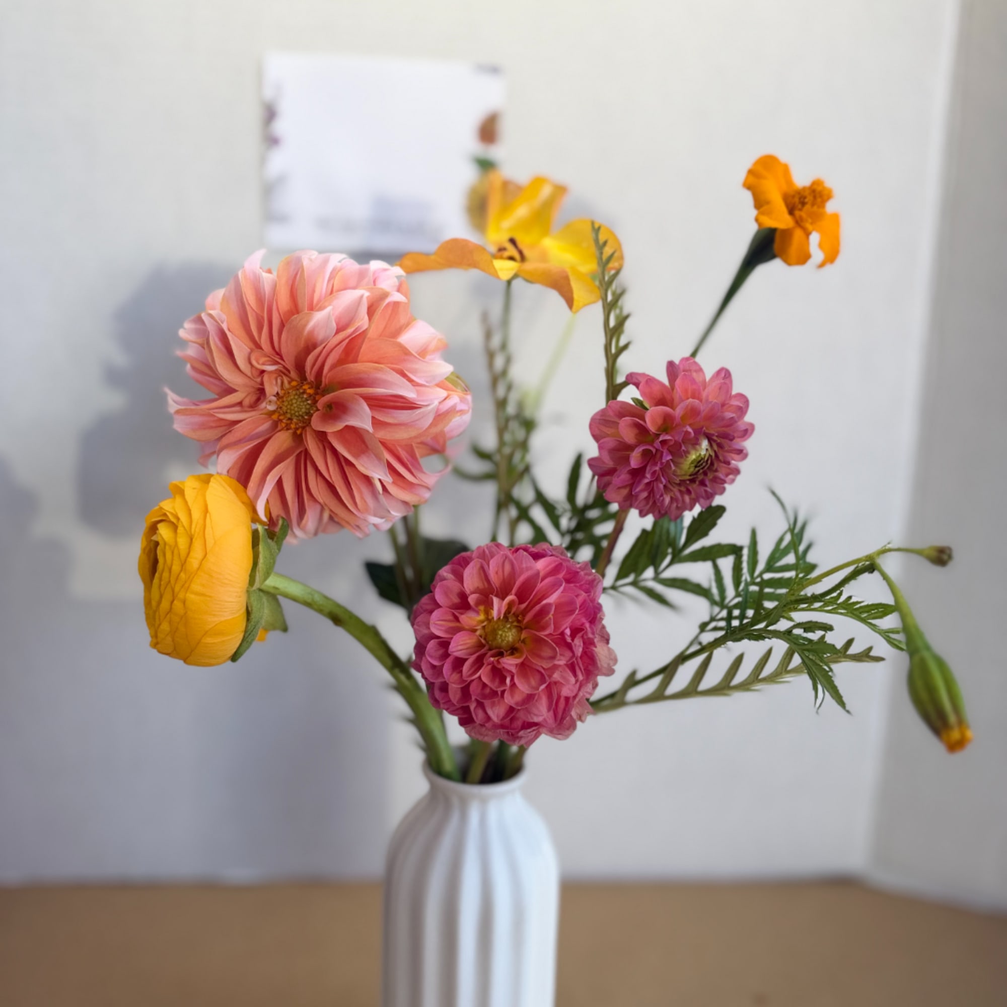 Pink and yellow flowers in a white vase