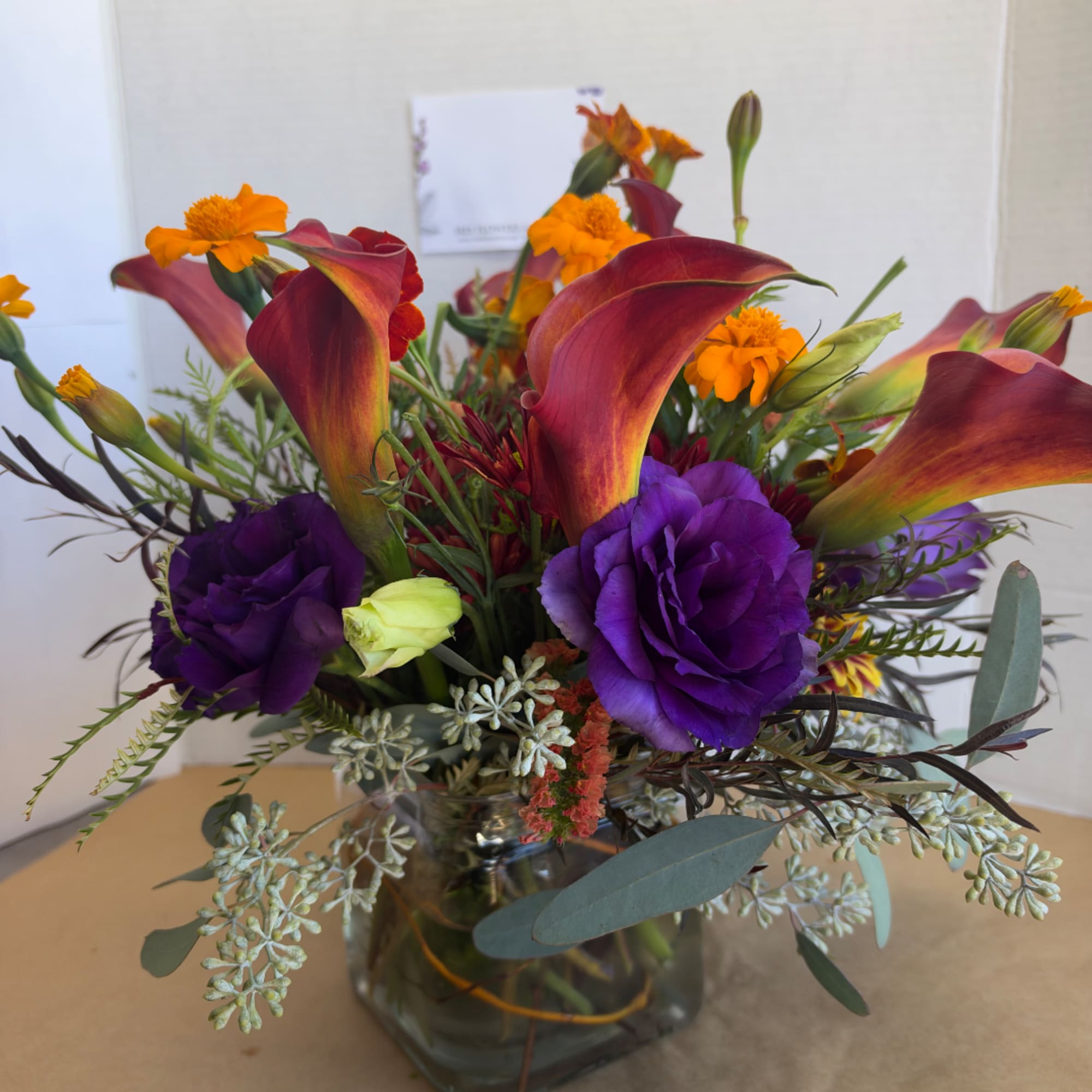 Purple and orange floral arrangement in a glass vase