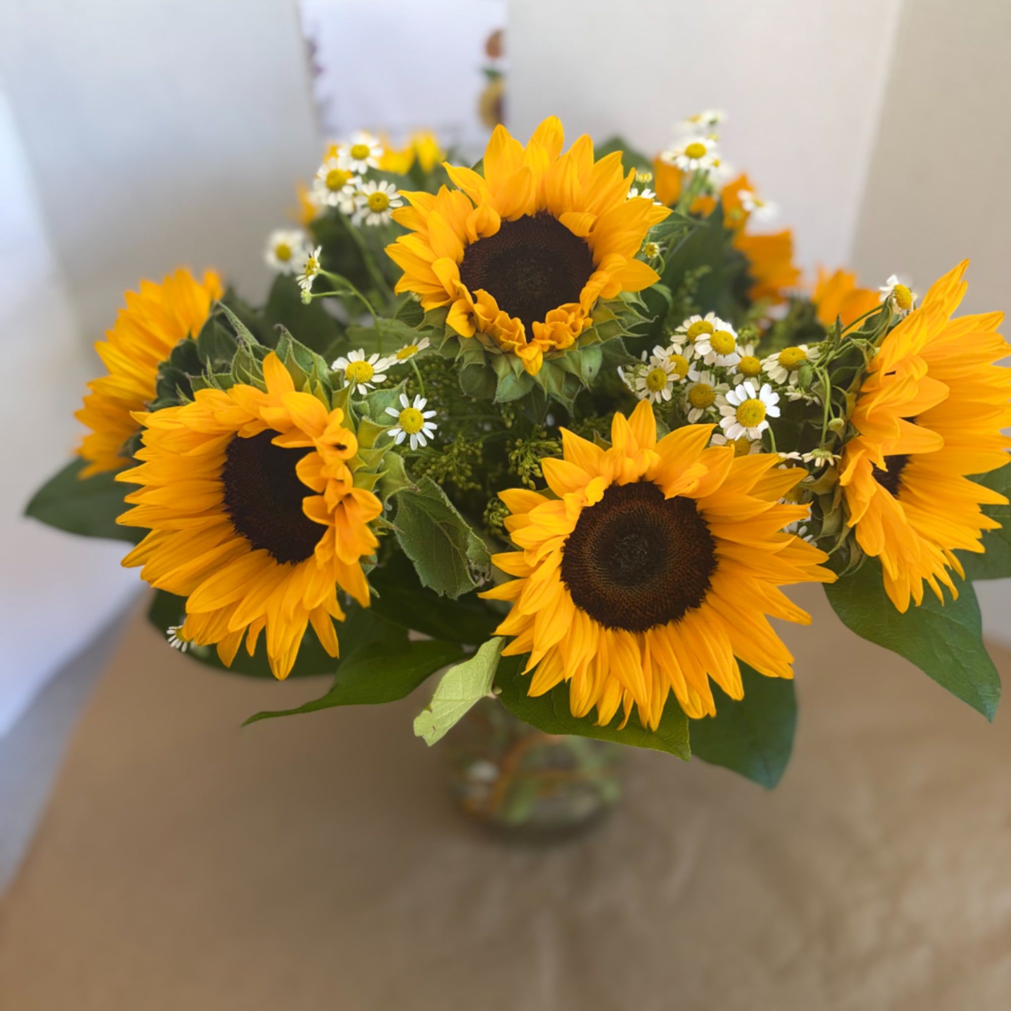 Bouquet of yellow sunflowers with small white daisies in a glass vase