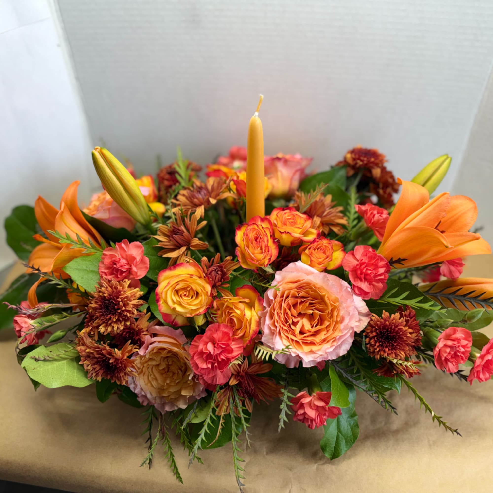 Orange and pink floral centerpiece with a single candle in the middle