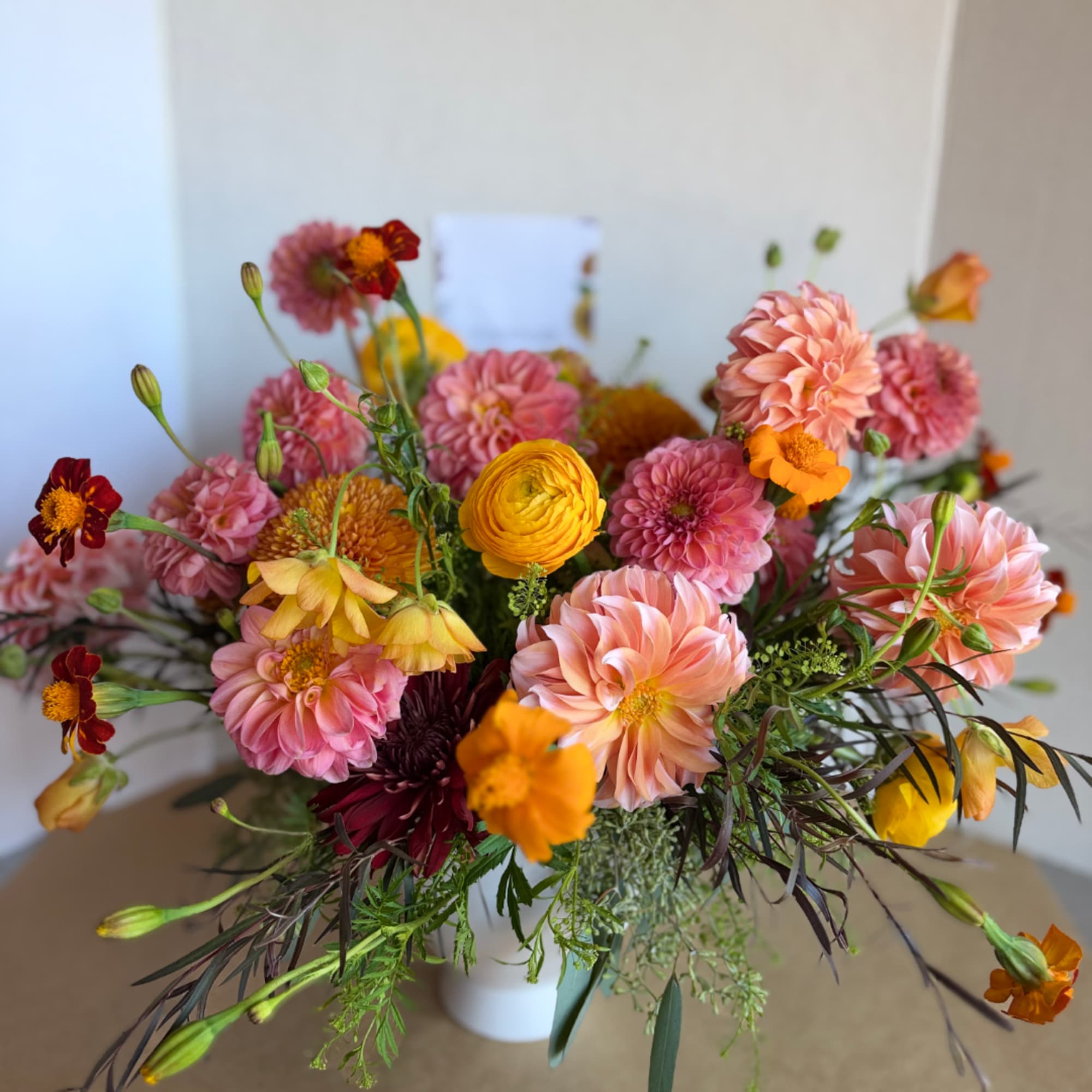 Pink and peach mixed flower bouquet in a white vase