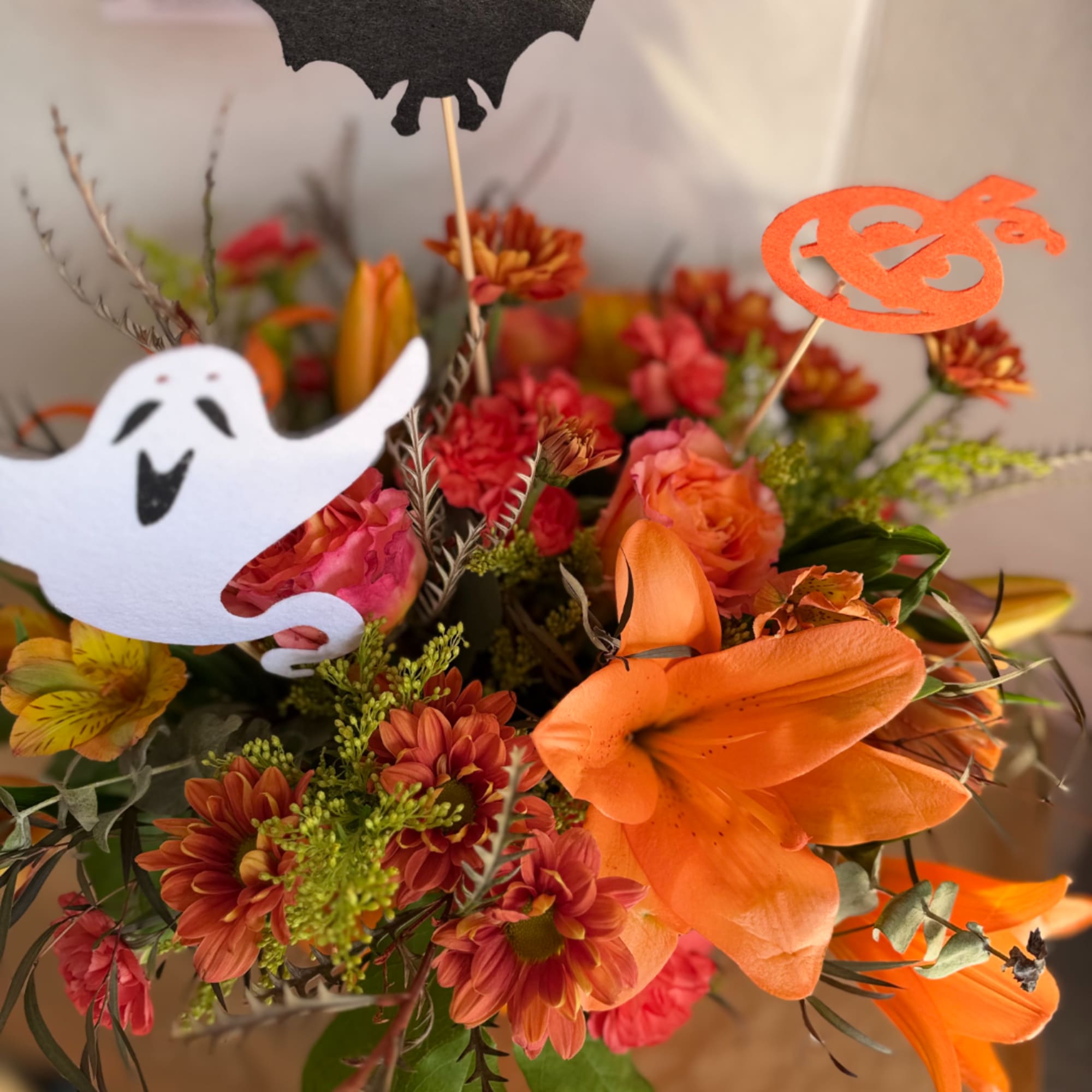 Halloween bouquet with orange lilies, chrysanthemums, and ghost picks