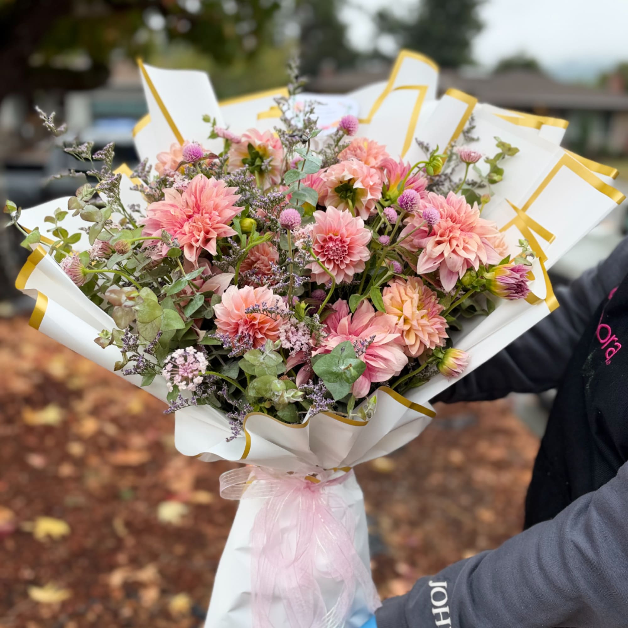 Pink dahlia bouquet wrapped in white paper with gold trim, photo 3 of 4