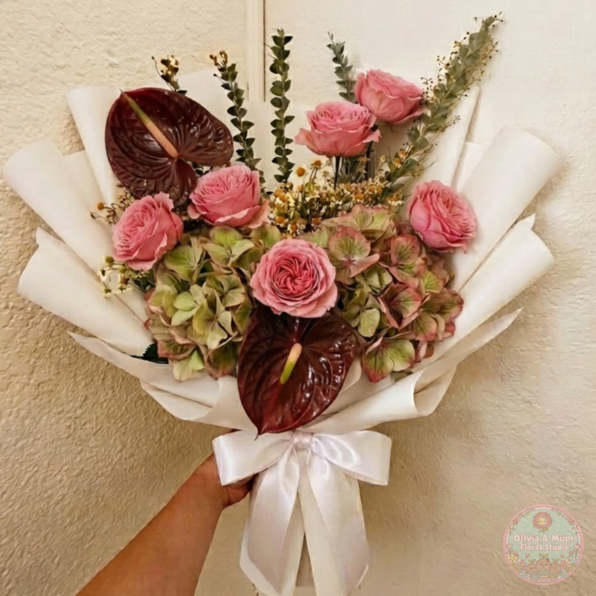 Pink roses and hydrangeas in white wrapping with a satin bow