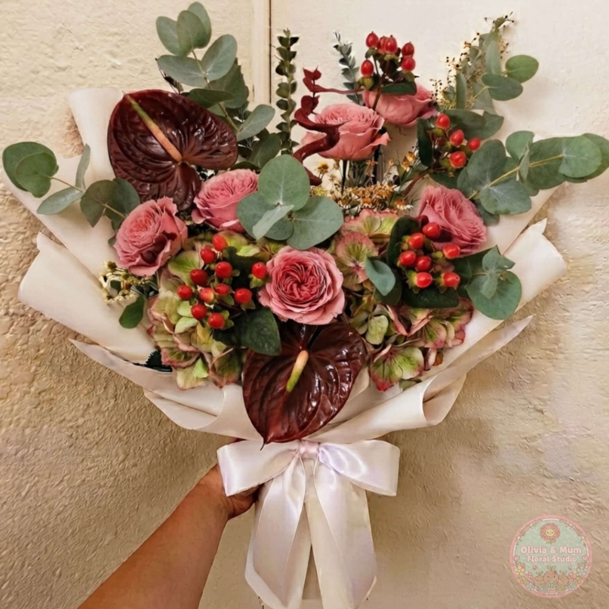 Hand-tied bouquet of pink roses and dark anthuriums with eucalyptus