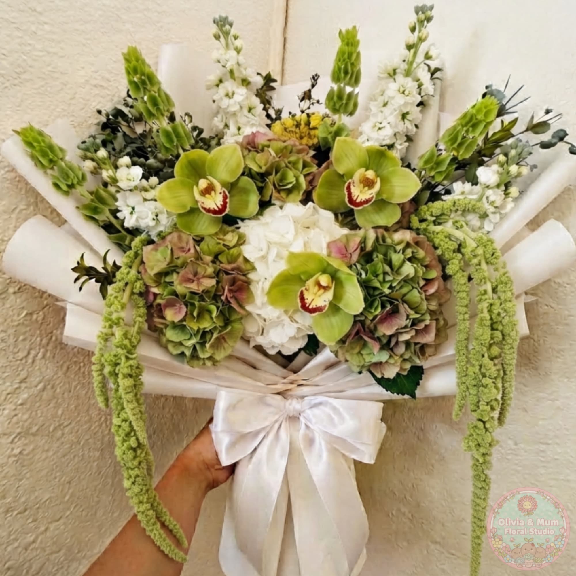 Bouquet of green orchids, white flowers, and hydrangeas wrapped in white paper