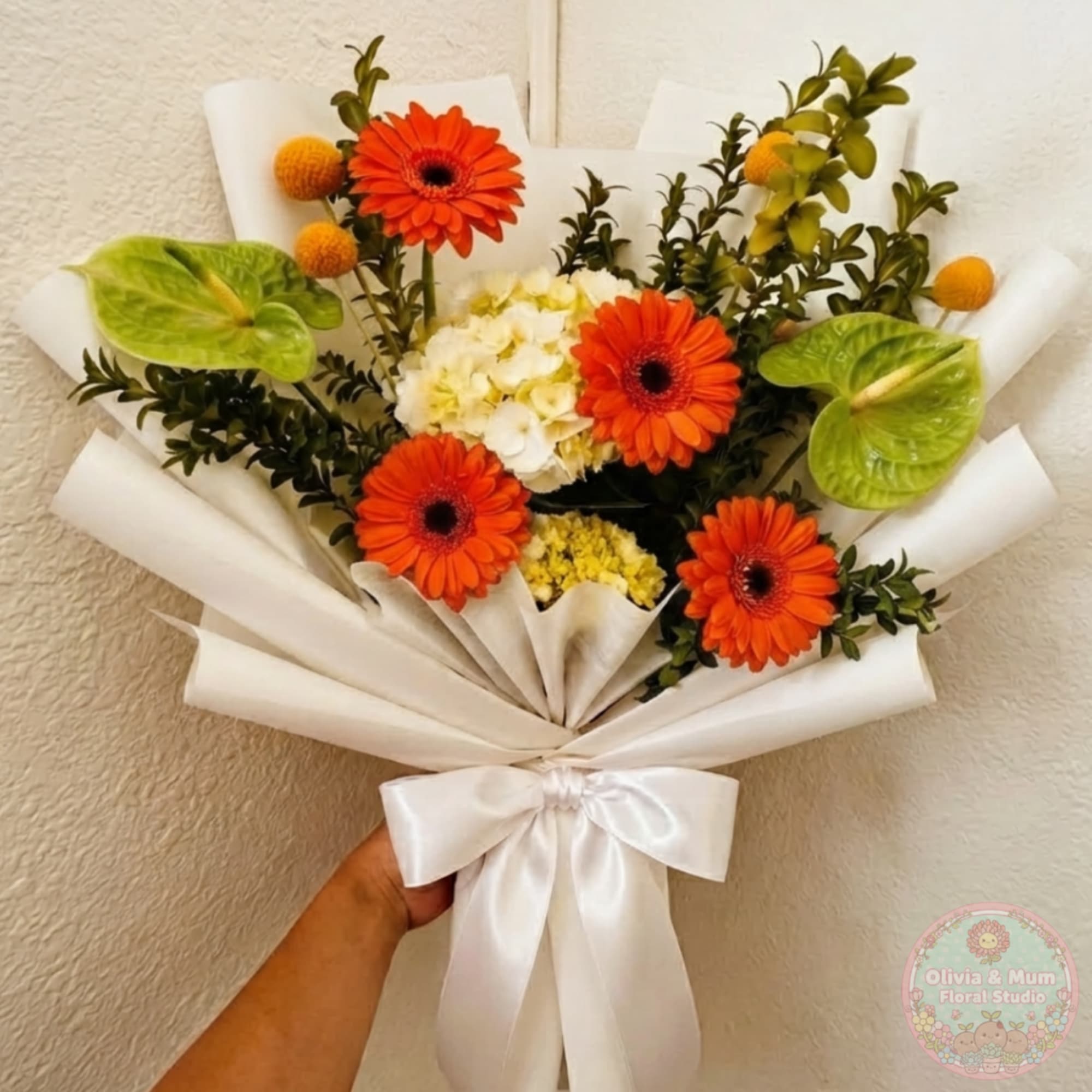 Bouquet of orange gerbera daisies, white hydrangea, and green anthuriums wrapped in white paper