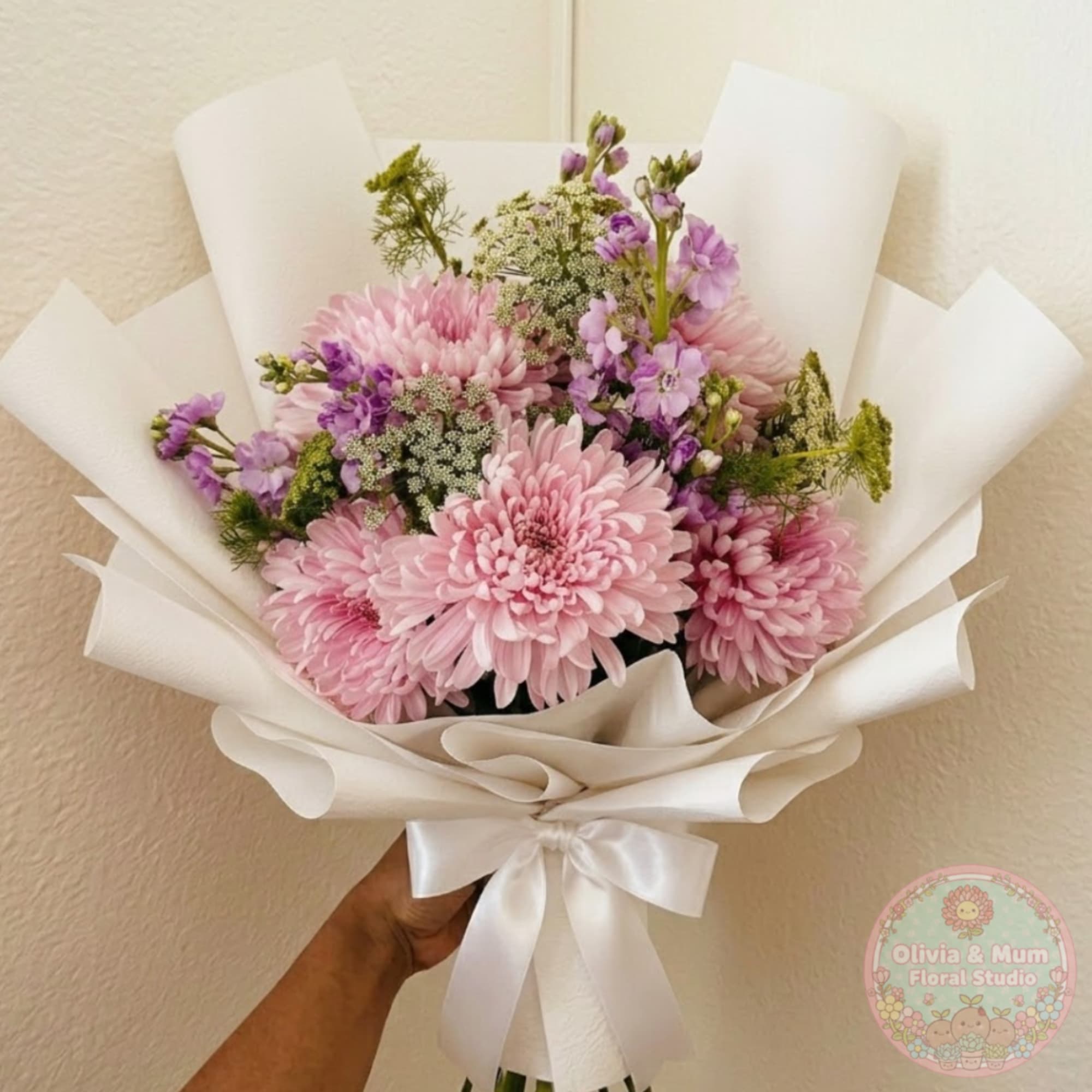 Pink chrysanthemum bouquet wrapped in white paper with a satin ribbon