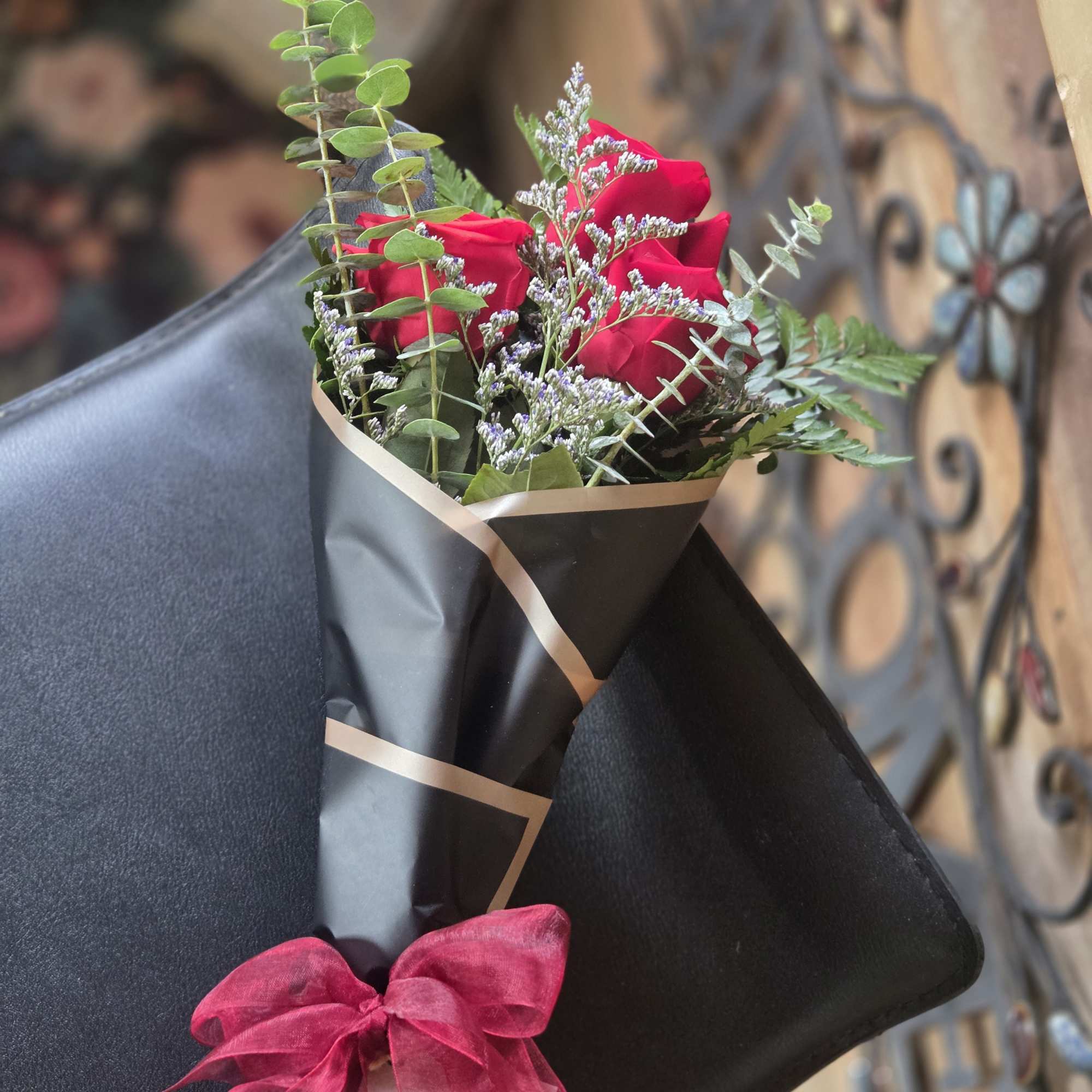 Bouquet of red roses wrapped in black paper with a pink bow