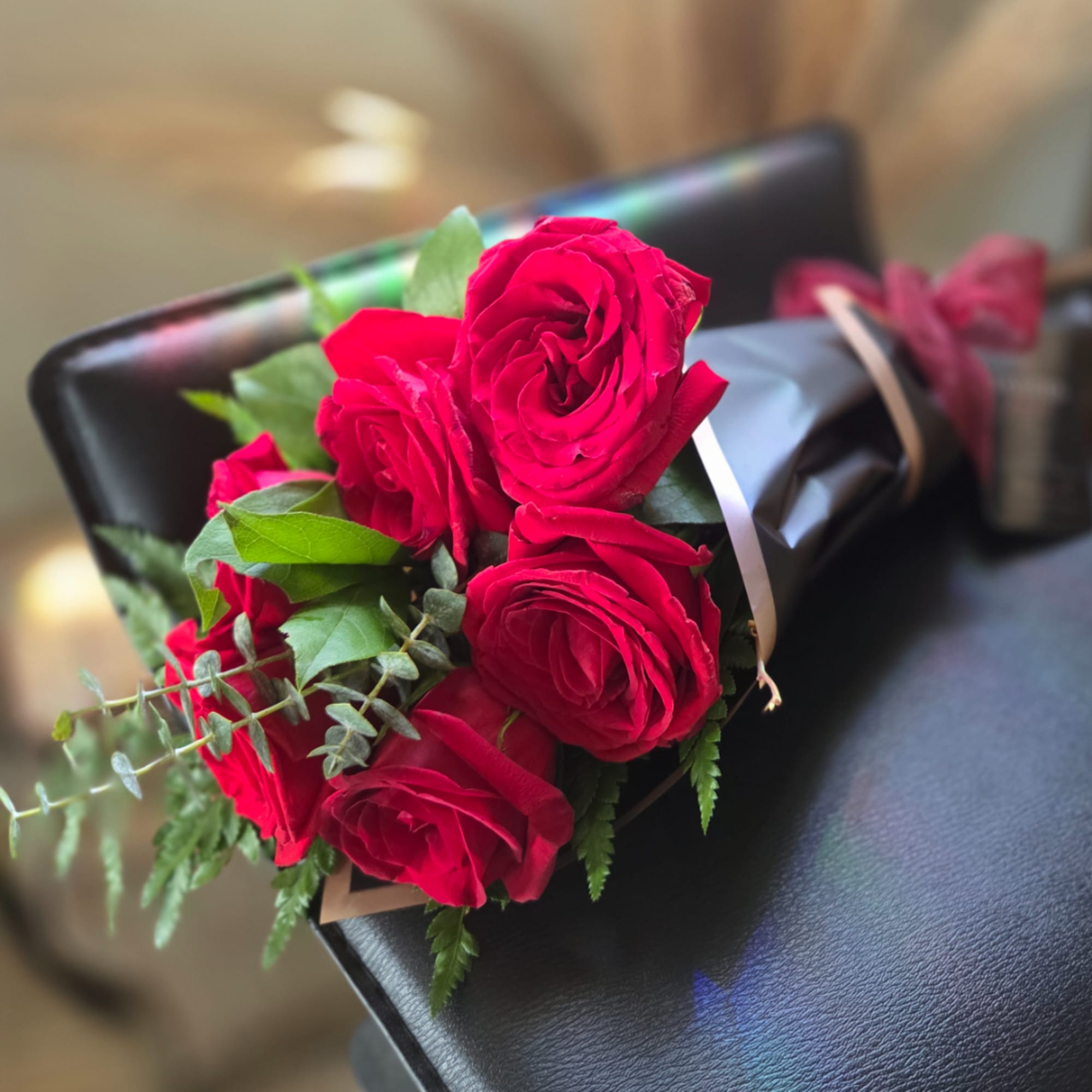 Bouquet of red roses wrapped in black paper with a ribbon