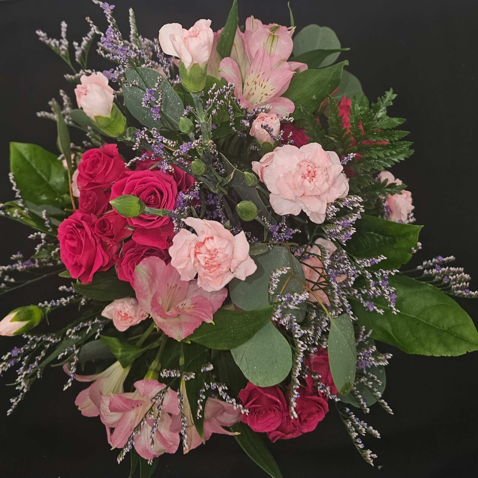 Bouquet of pink roses, carnations, and alstroemeria with purple filler flowers