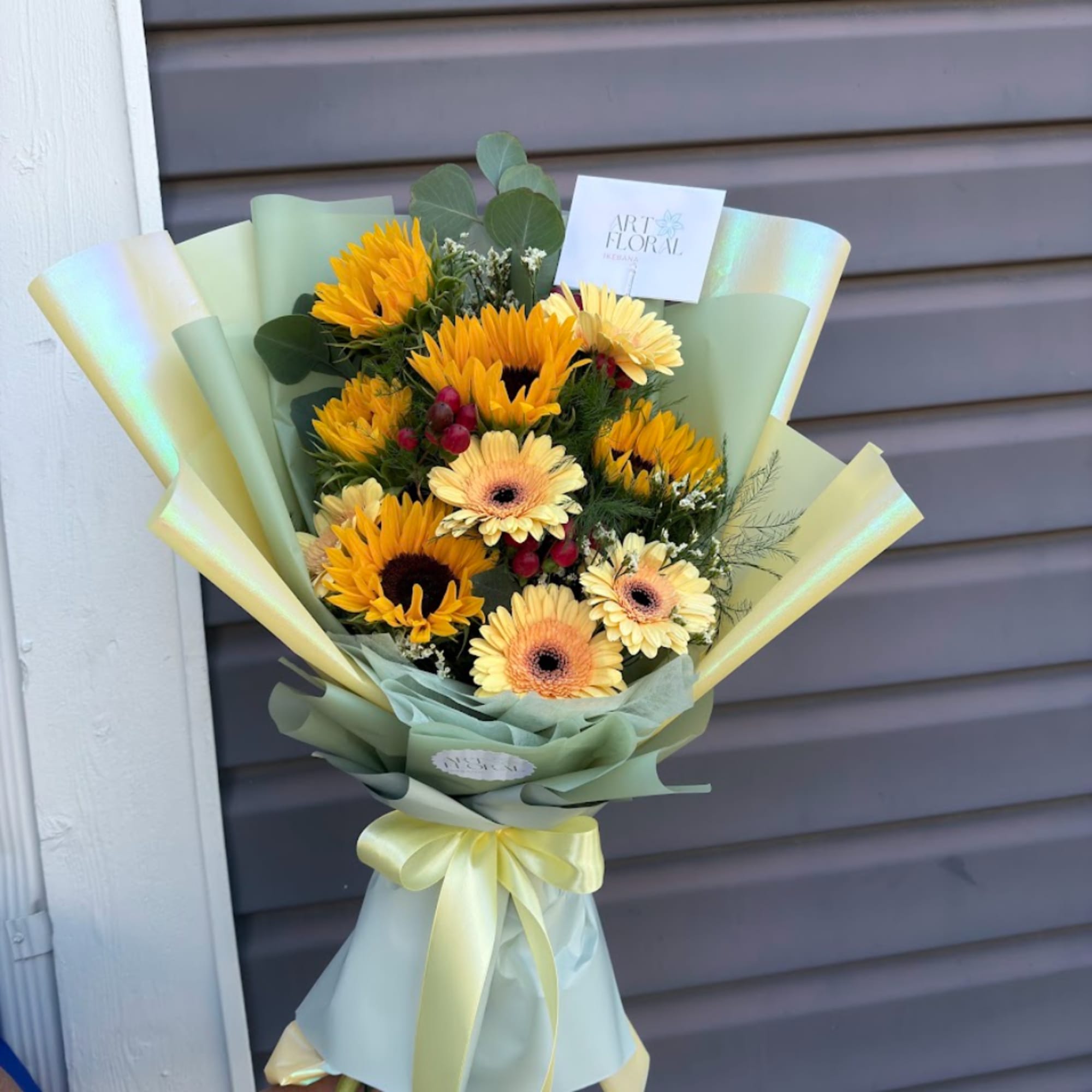 Bouquet of sunflowers and pale gerbera daisies wrapped in pastel paper, photo 3 of 3