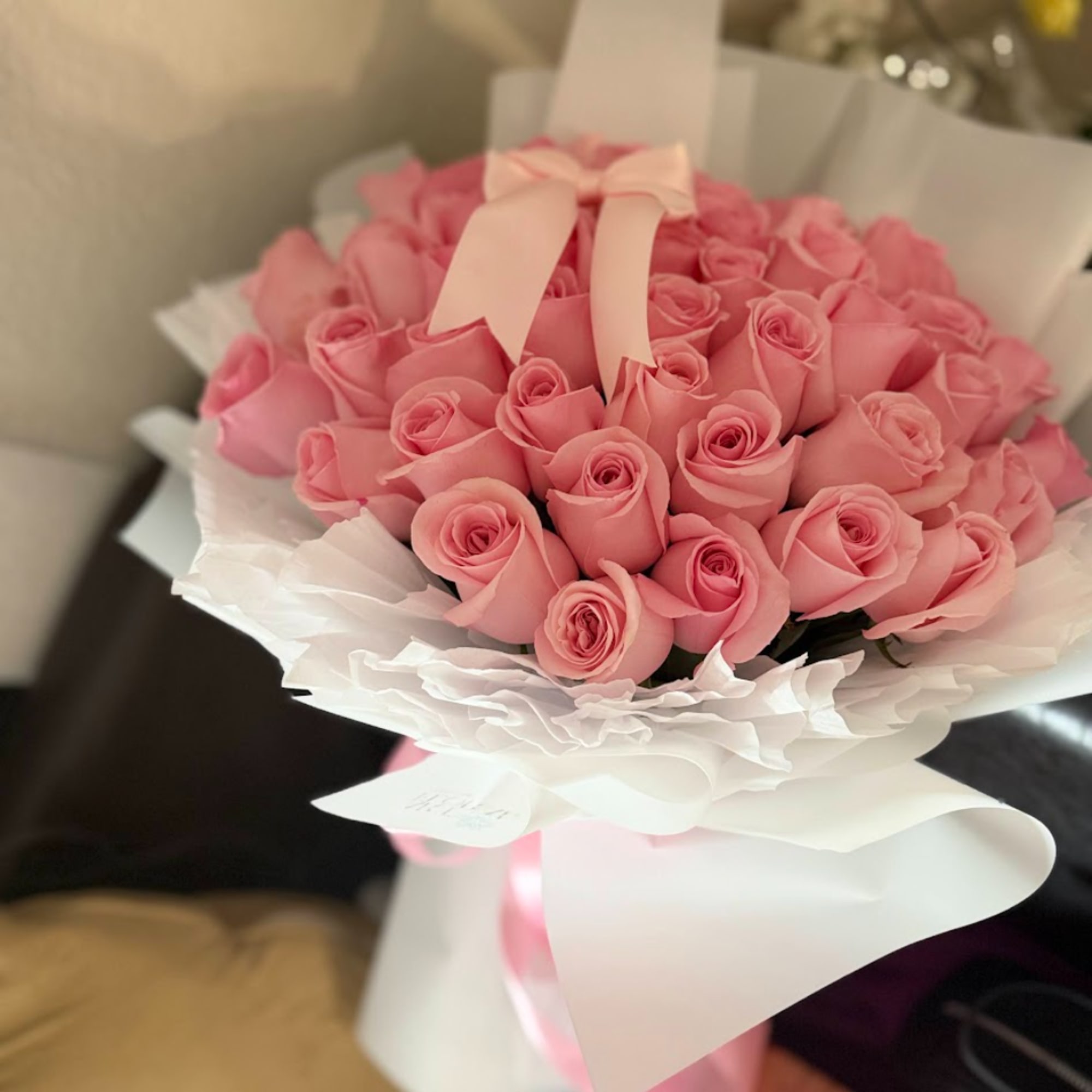 Bouquet of pink roses wrapped in white paper with a ribbon