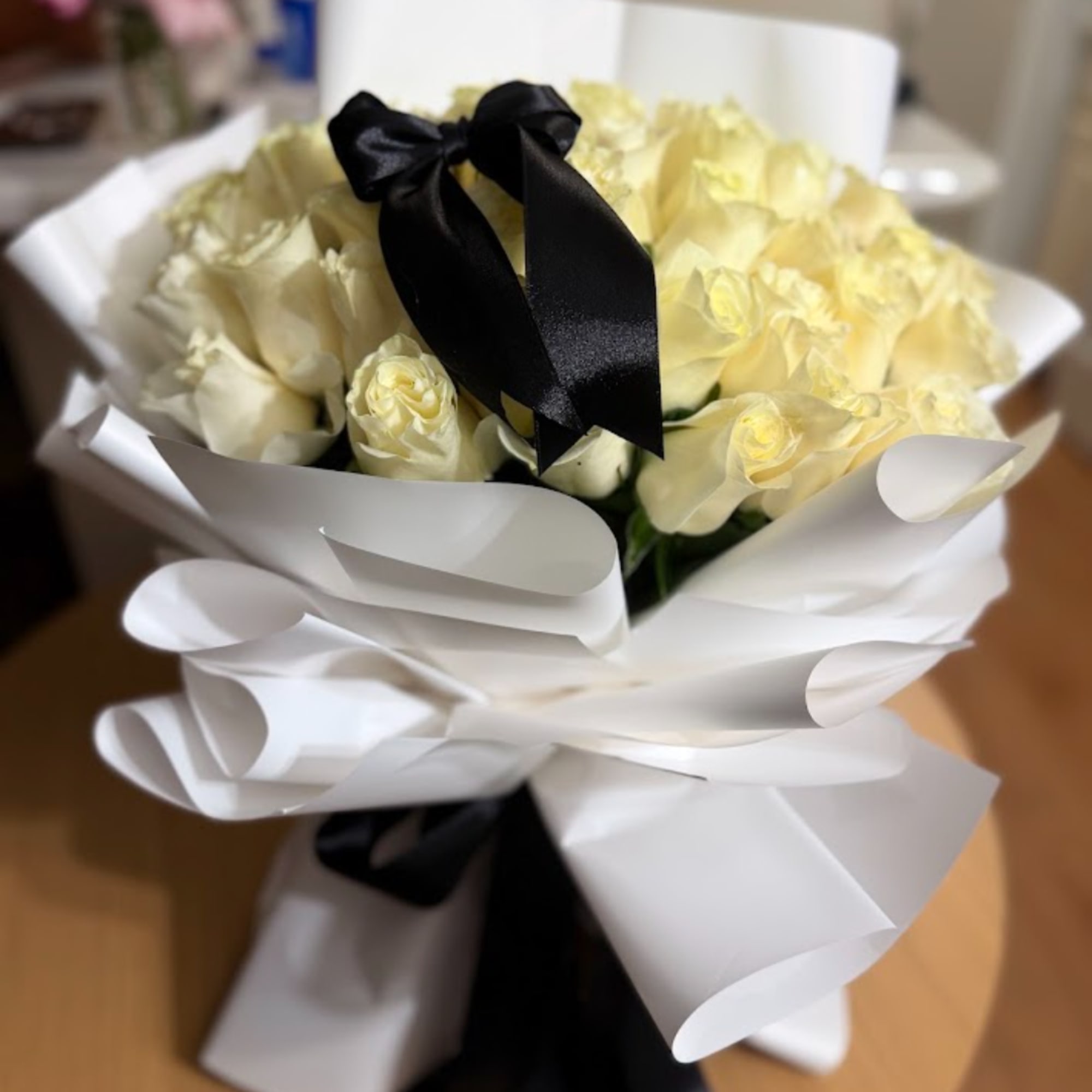 Bouquet of pale yellow roses wrapped in white paper with a black ribbon, photo 2 of 2