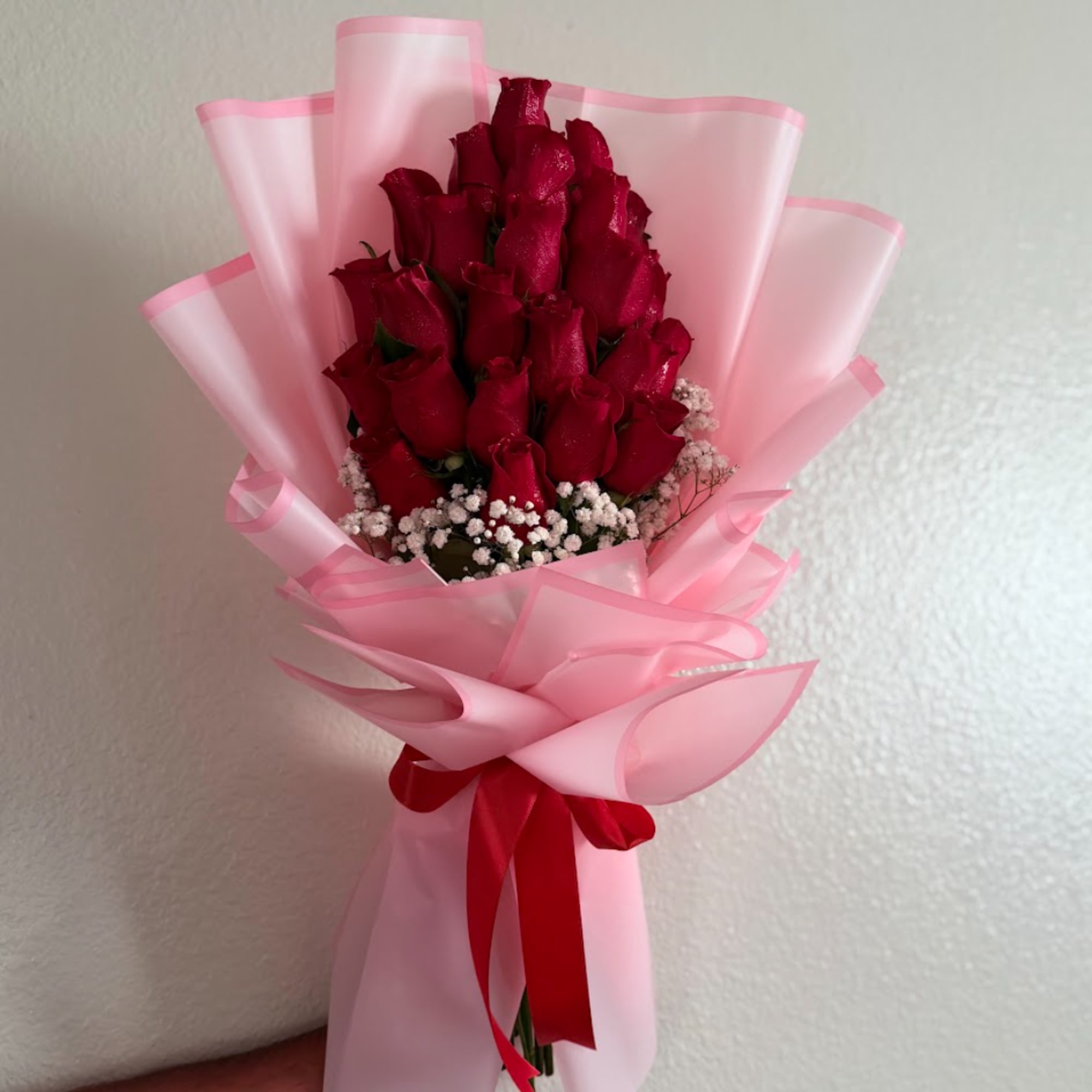 Bouquet of red roses wrapped in pink paper with a red ribbon