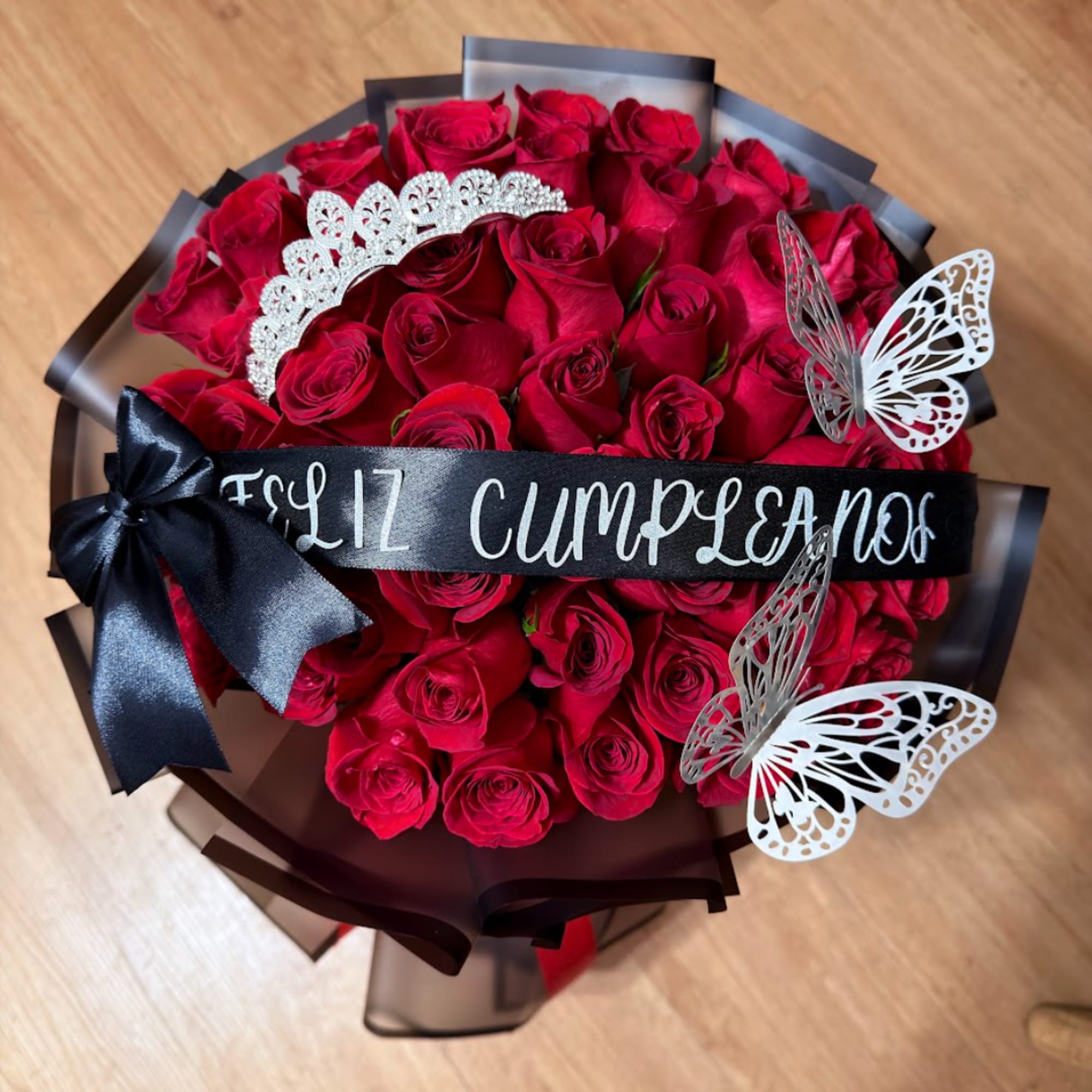 Bouquet of red roses wrapped in black paper with a birthday ribbon