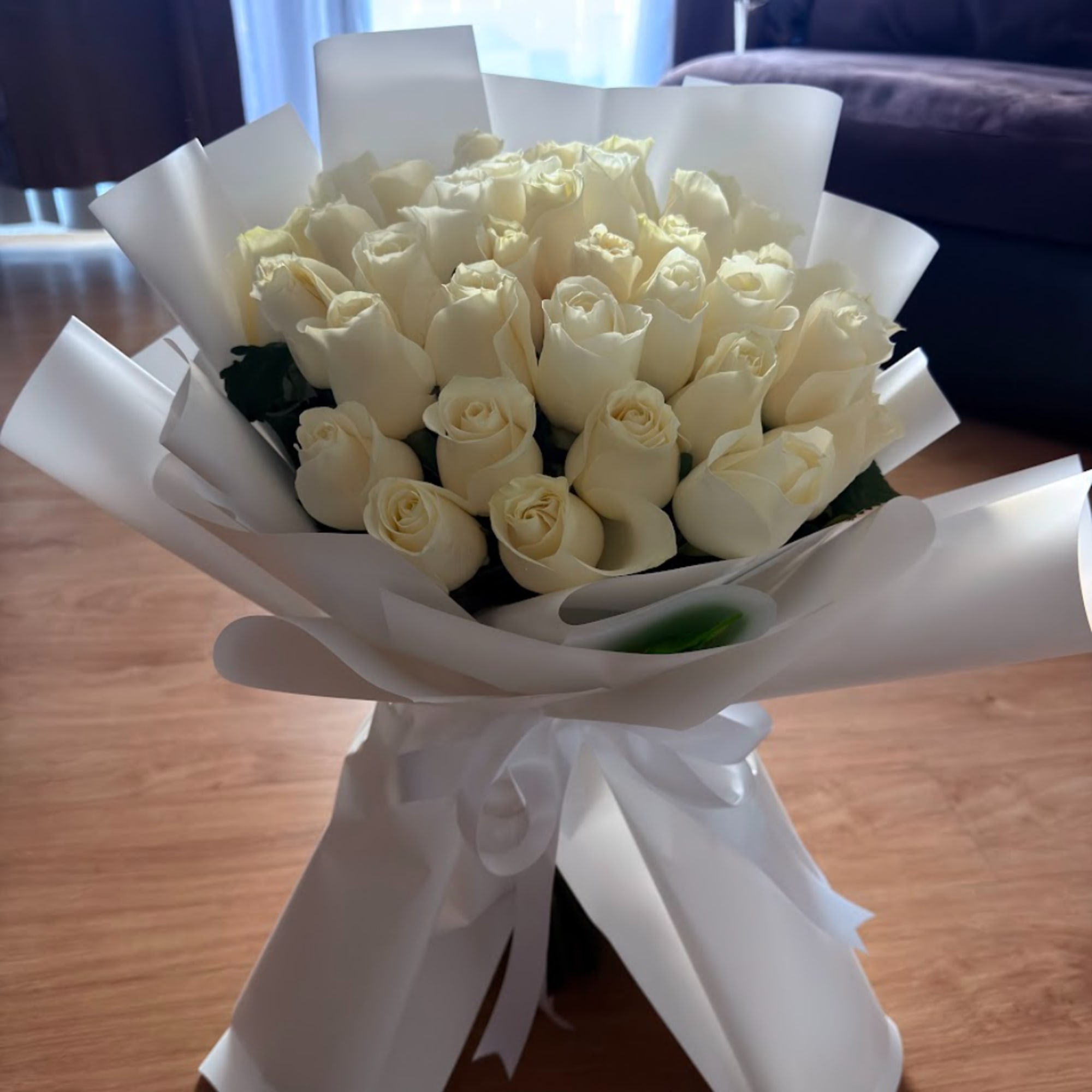 Bouquet of cream white roses wrapped in white paper with a ribbon