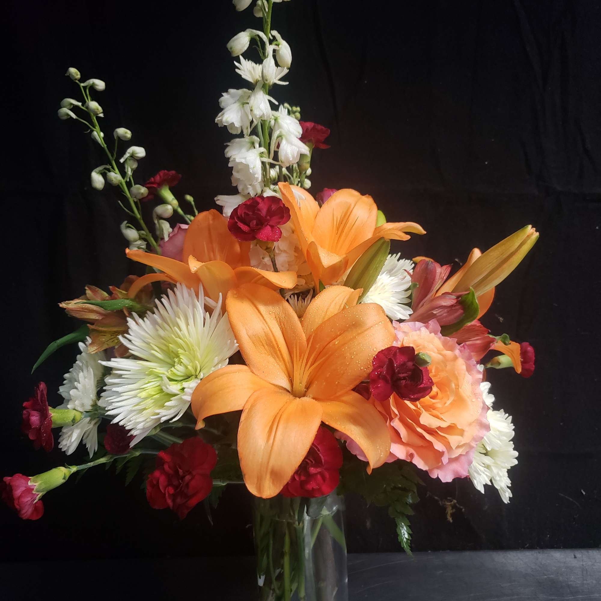 Bright orange lilies take center stage in this cheerful flower arrangement, making