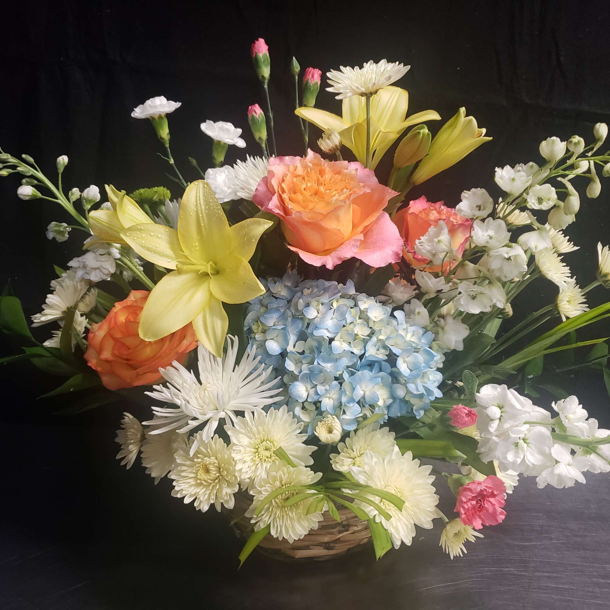 A lush cluster of blue hydrangeas anchors this event arrangement, surrounded by