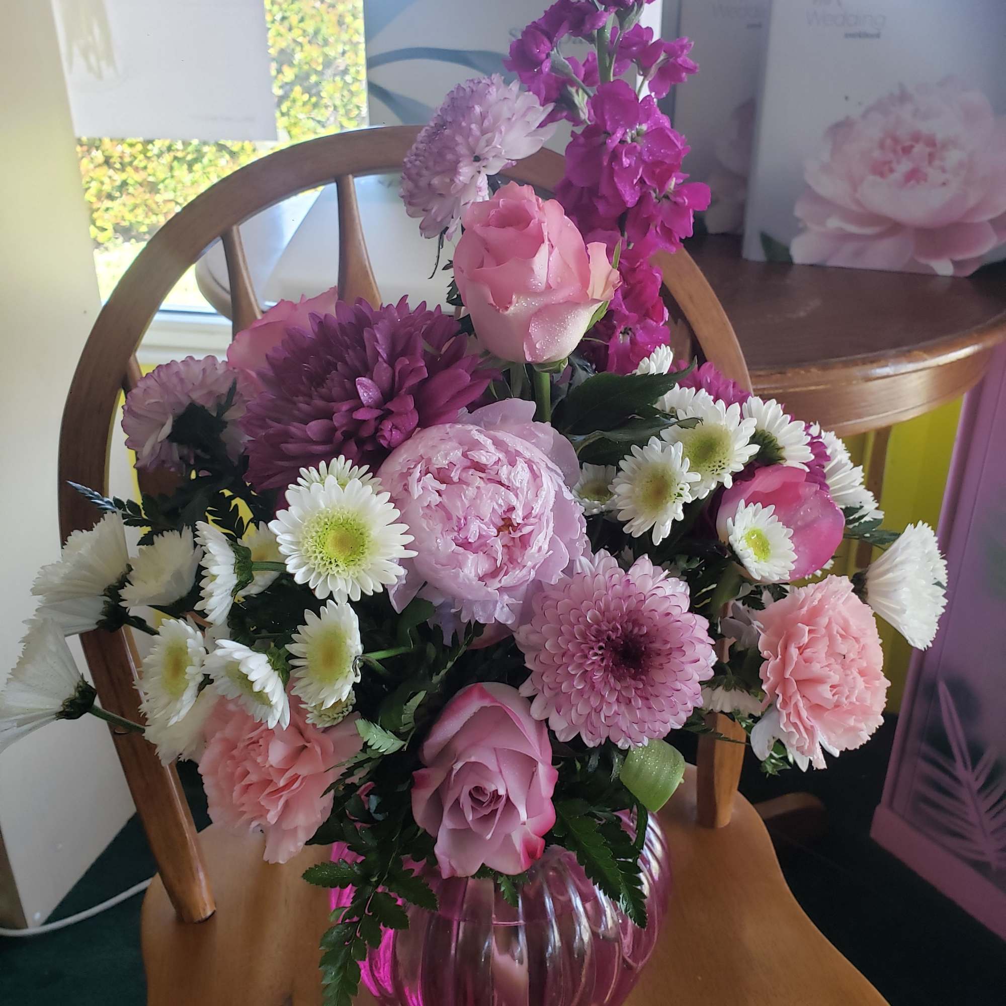 A lush cluster of pink, lavender, purple, and white roses, carnations, chrysanthemums