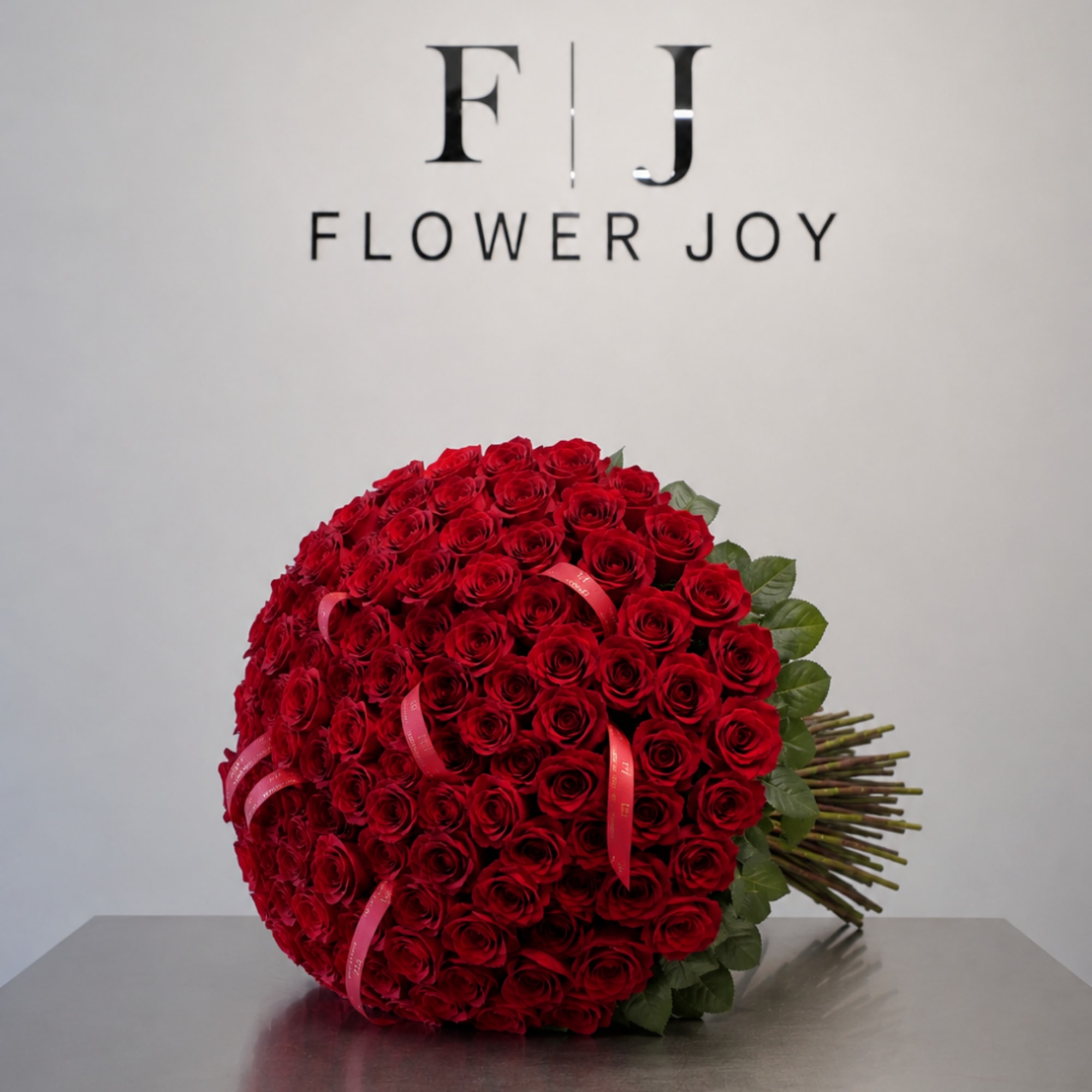 Large round bouquet of red roses with pink ribbon accents