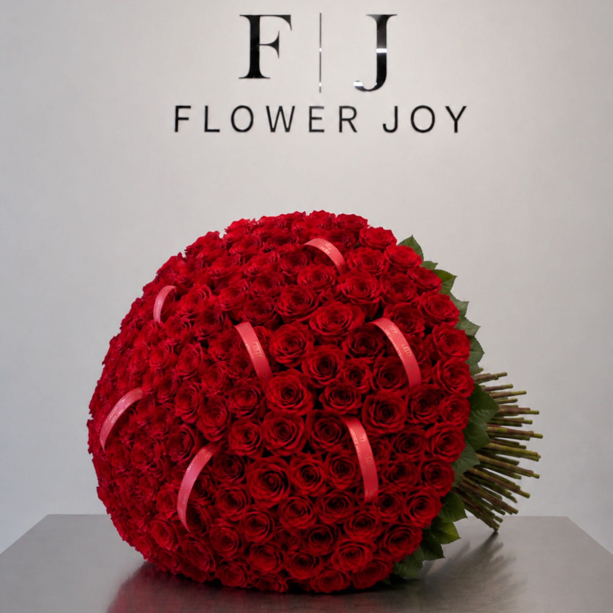 Large round bouquet of red roses with pink ribbon accents