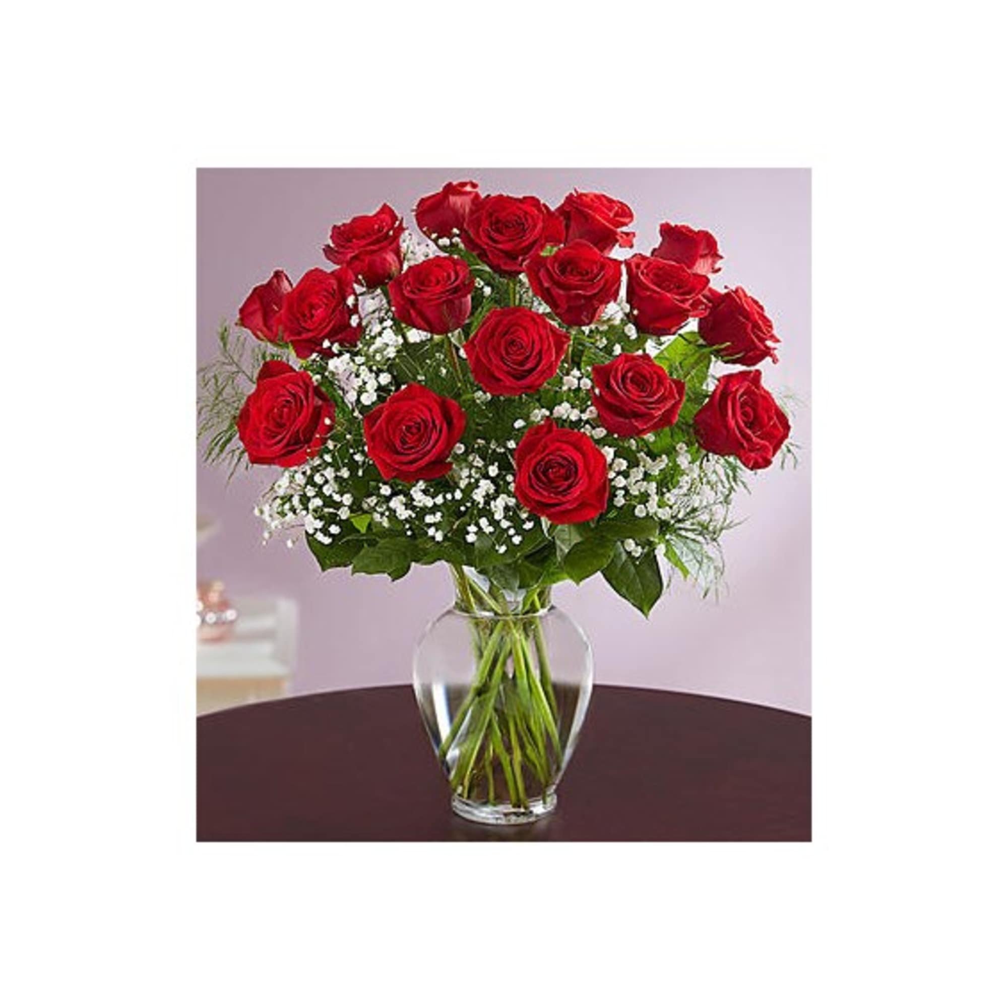 Red roses arranged in a clear glass vase with white filler flowers