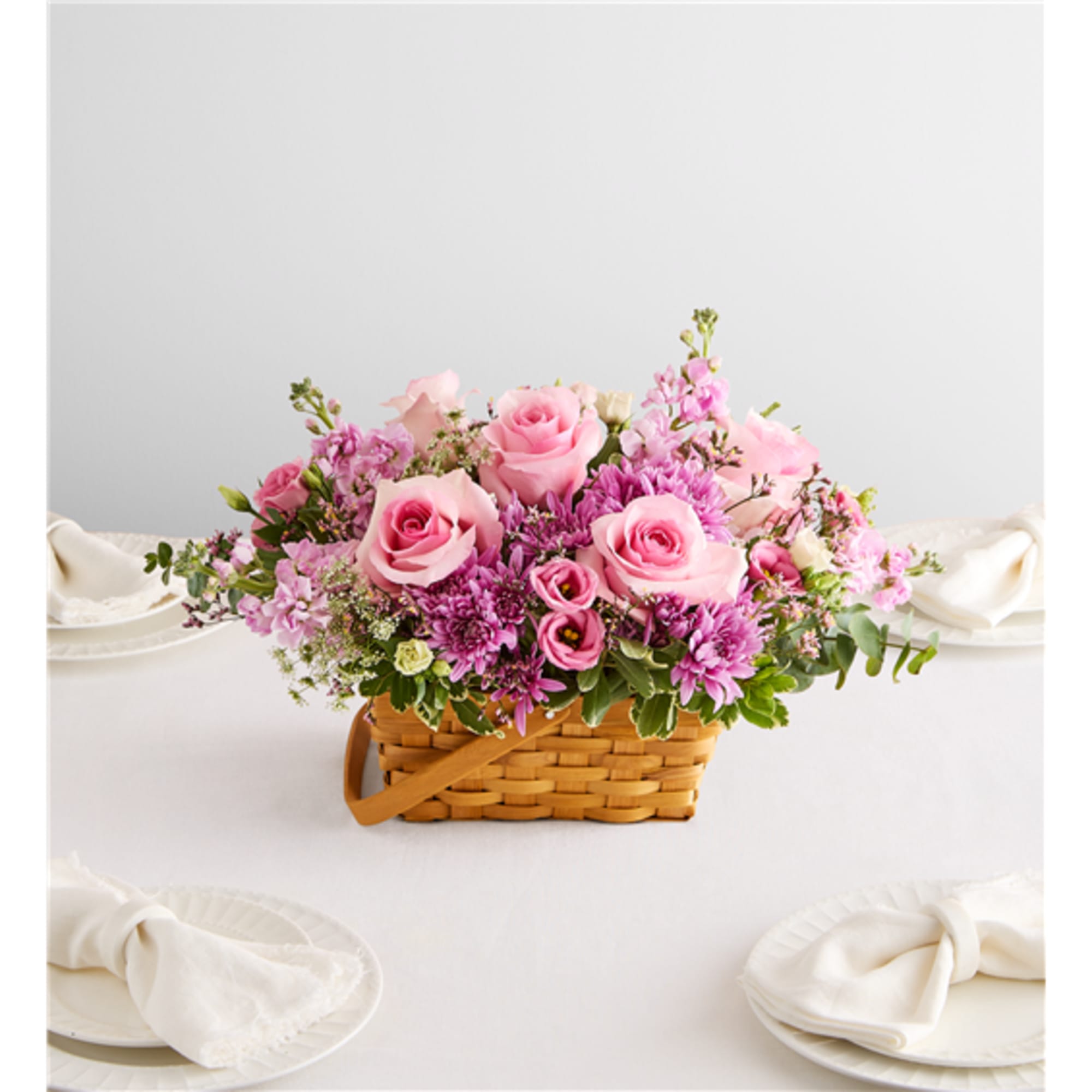 Pink roses and purple flowers arranged in a wicker basket