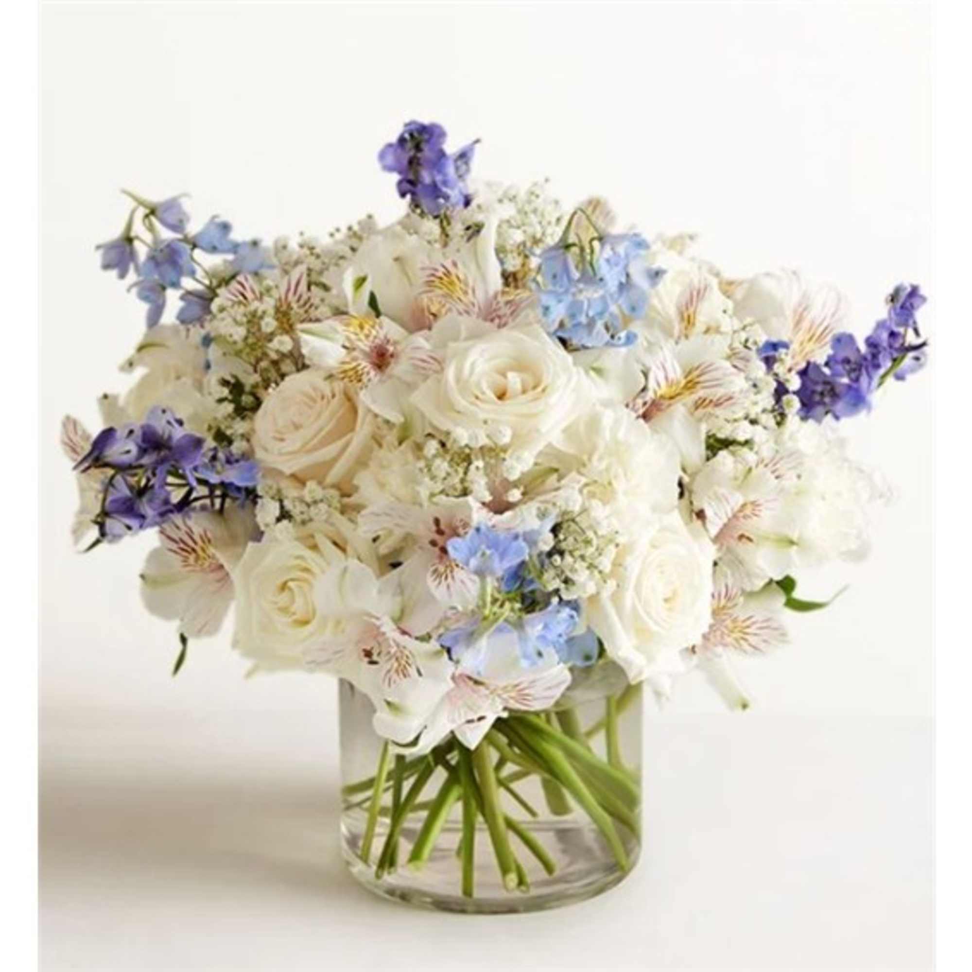 White roses and pale blue flowers in a clear glass vase