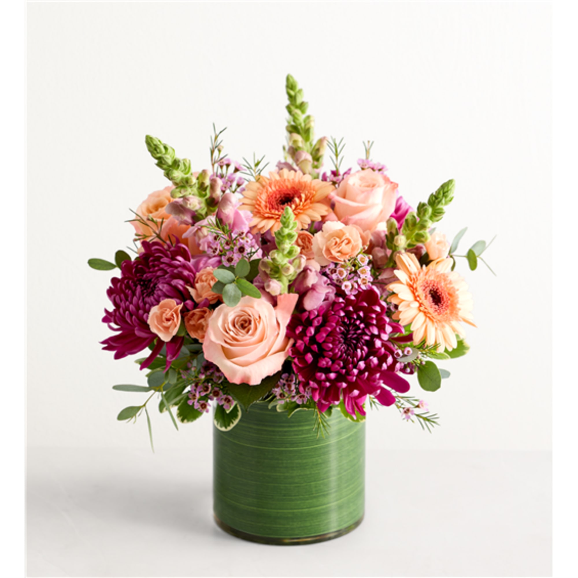 Mixed pink and peach flowers arranged in a green vase