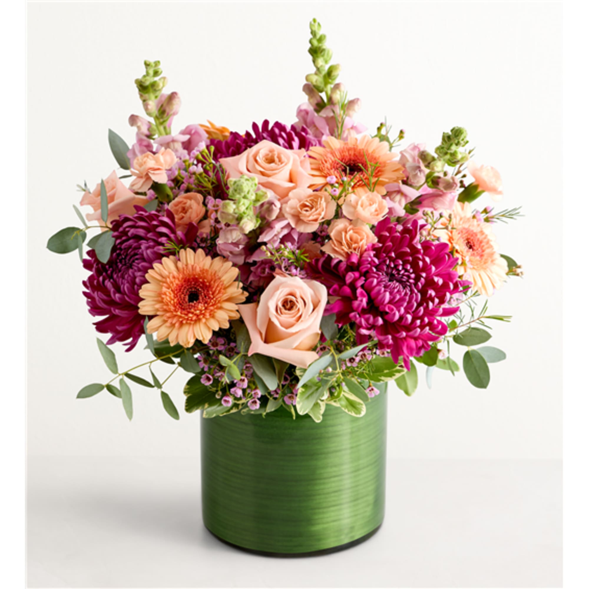 Mixed pink and peach flowers in a green cylindrical vase