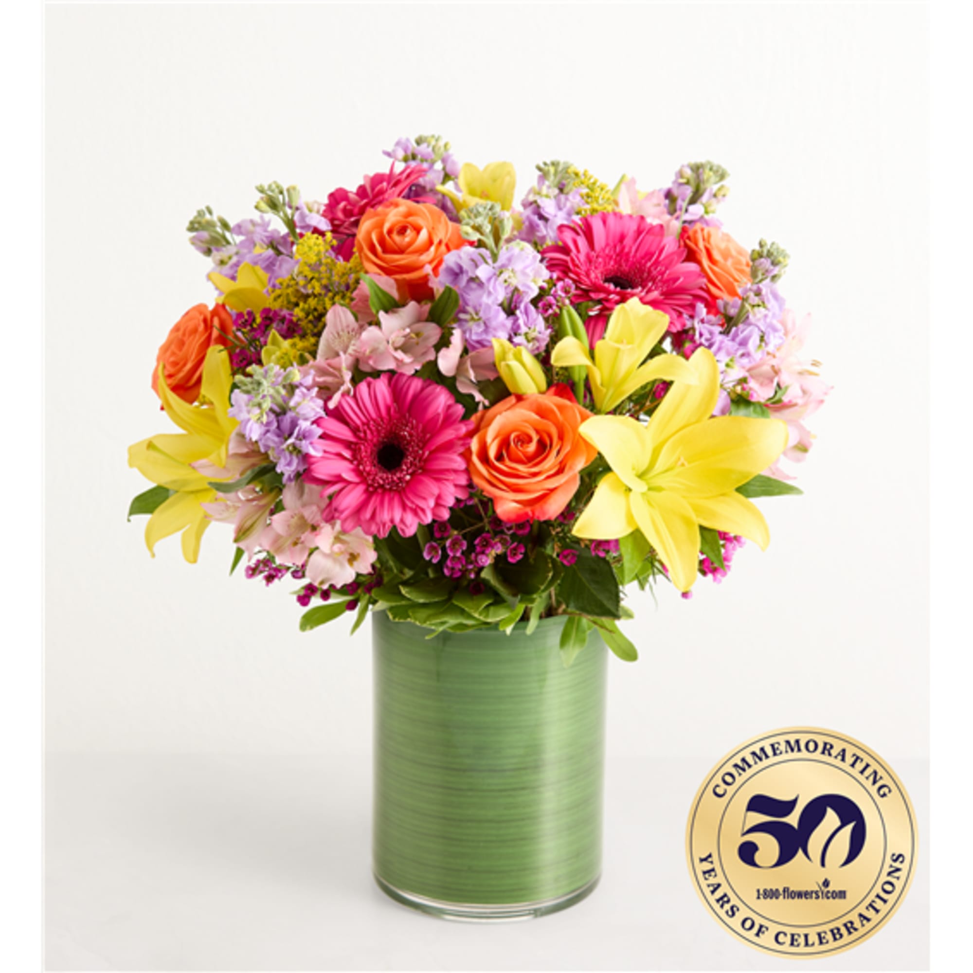 Mixed bouquet of roses, lilies, and gerbera daisies in a green vase