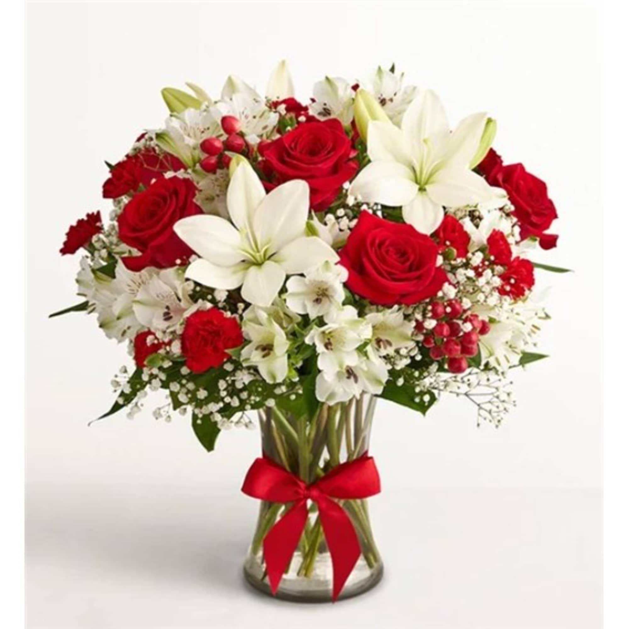 Bouquet of red roses and white lilies in a clear glass vase with a red ribbon