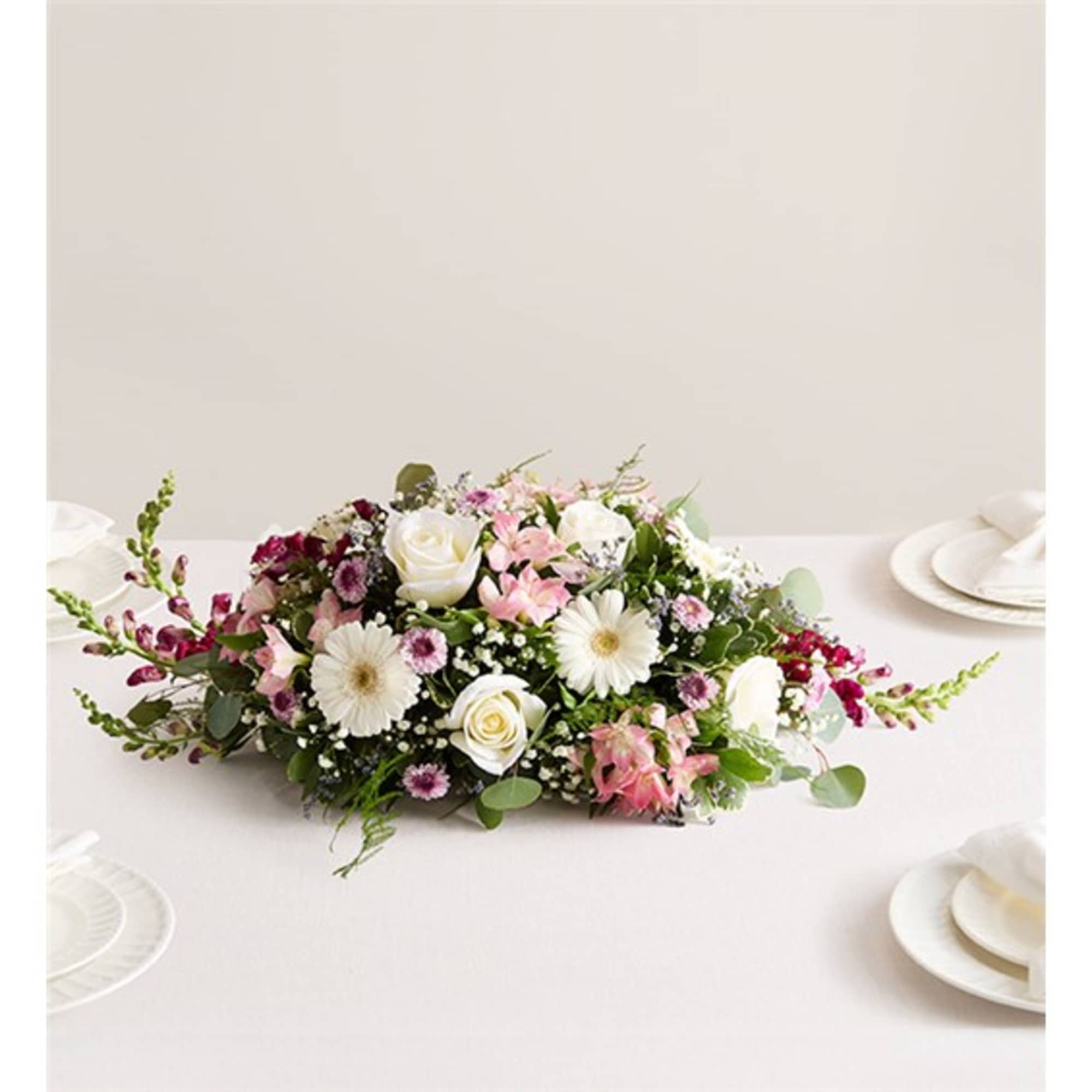 Low floral centerpiece with white and pink blooms on a table