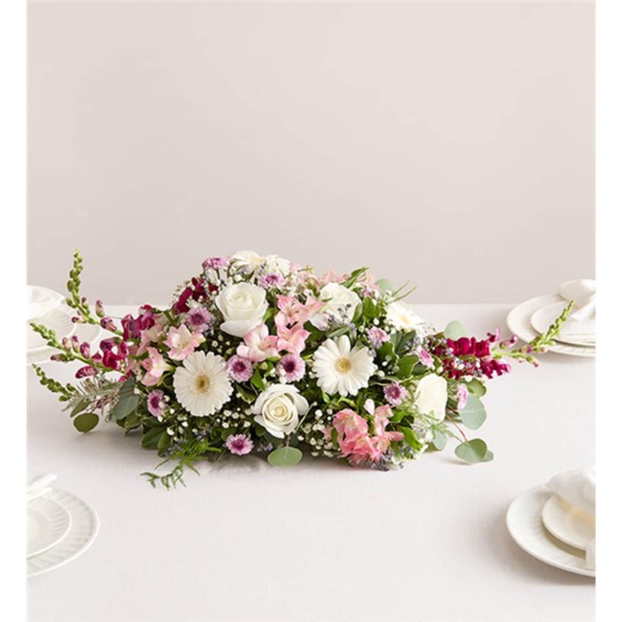 Low floral centerpiece with white, pink, and magenta blooms on a table